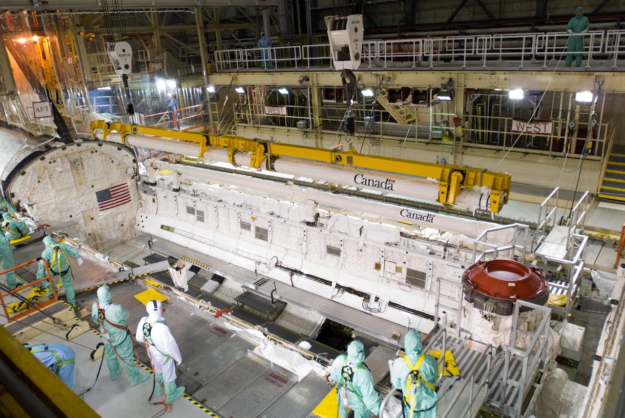 CAPE CANAVERAL, Fla. – In the Orbiter Processing Facility’s bay 3, the orbiter boom sensor system is moved into position by a crane over space shuttle Discovery for installation in its payload bay to support mission STS-128.  The 50-foot-long boom attaches to the shuttle arm and provides equipment to inspect the shuttle's heat shield while in space. It contains an intensified television camera (ITVC) and a laser dynamic range imager, which are mounted on a pan and tilt unit, and a laser camera system (LCS) mounted on a stationary bracket.  The STS-128 flight will carry science and storage racks to the International Space Station on space shuttle Discovery. Launch of Discovery is targeted for Aug. 6. Photo credit: NASA_Jim Grossmann