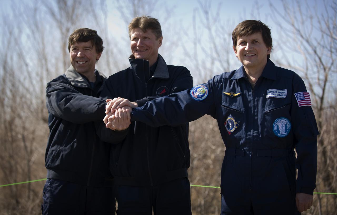 Expedition 19 Flight Engineer Michael R. Barratt, left, Commander Gennady I. Padalka, center, and Spaceflight Participant Charles Simonyi pose for a photograph after the traditional tree planting ceremony at the Cosmonaut Hotel, Saturday, March 21, 2009 in Baikonur, Kazakhstan.  (Photo Credit: NASA/Bill Ingalls)