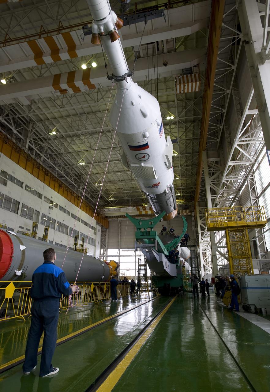 An engineer assists in maneuvering the Soyuz TMA-14 spacecraft and third stage for final assembly to the first and second stages Monday, March 23, 2009 at the Baikonur Cosmodrome in Kazakhstan. The Soyuz is scheduled to launch the crew of Expedition 19 and a spaceflight participant on March 26, 2009. Photo Credit: (NASA/Bill Ingalls)