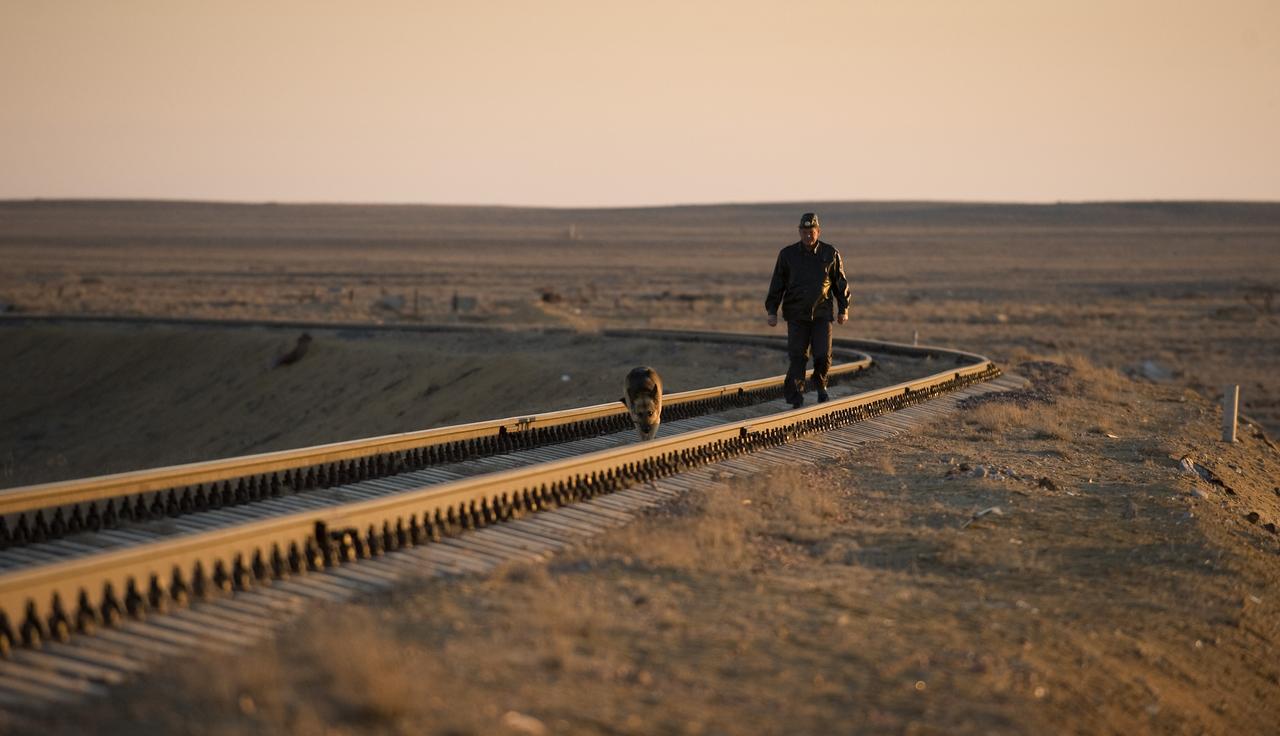 A Russian security member and his dog check the railroad tracks ahead of the Soyuz rocket roll out to the launch pad Tuesday, March 24, 2009 at the Baikonur Cosmodrome in Kazakhstan. The Soyuz is scheduled to launch the crew of Expedition 19 and a spaceflight participant on March 26, 2009. Photo Credit: (NASA/Bill Ingalls)