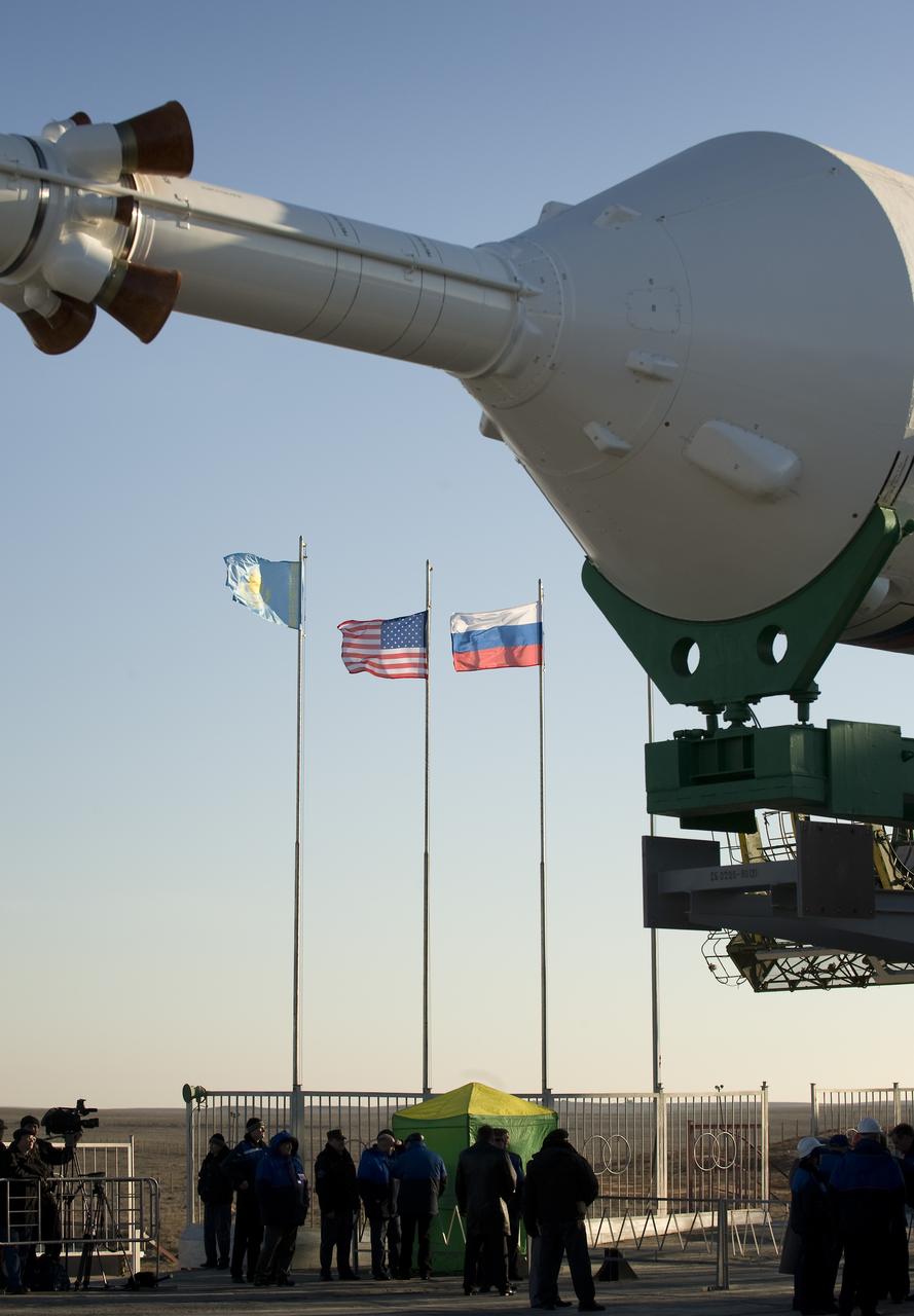 The flags of Kazakhstan, the United States of America and Russia are seen in the background as the Soyuz rocket is prepared to be erected into position at the launch pad Tuesday, March 24, 2009 at the Baikonur Cosmodrome in Kazakhstan. The Soyuz is scheduled to launch the crew of Expedition 19 and a spaceflight participant on March 26, 2009. Photo Credit: (NASA/Bill Ingalls)