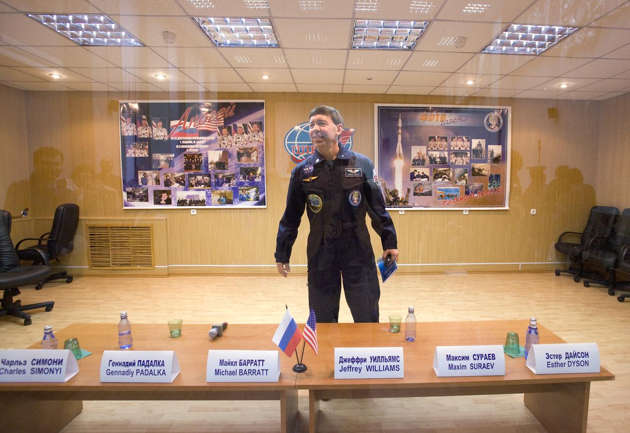 Expedition 19 Flight Engineer Michael R. Barratt smiles at his family from a  quarantined glass room after a press conference on Wednesday, March 25, 2009 at the Cosmonaut Hotel in Baikonur, Kazakhstan.  Photo Credit: (NASA/Bill Ingalls)