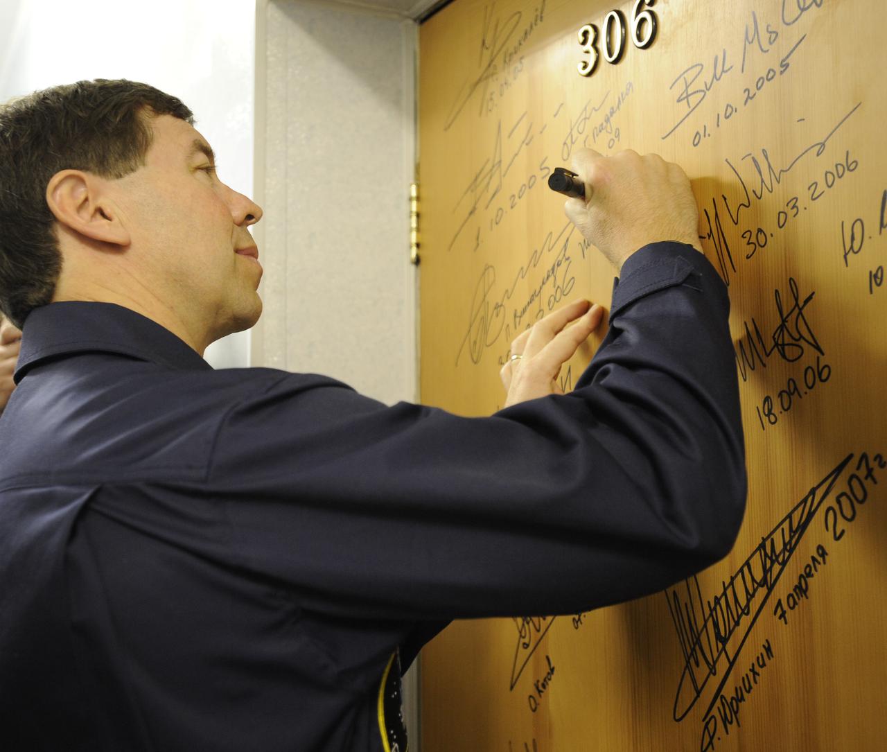 Expedition 19 Flight Engineer Michael R. Barratt performs the traditional door signing at the Cosmonaut Hotel on the morning of his Soyuz launch with Expedition 19 Commander Gennady I. Padalka and Spaceflight Participant Charles Simonyi to the International Space Station on Thursday, March 26, 2009 in Baikonur, Kazakhstan. (Photo Credit: NASA/Bill Ingalls)