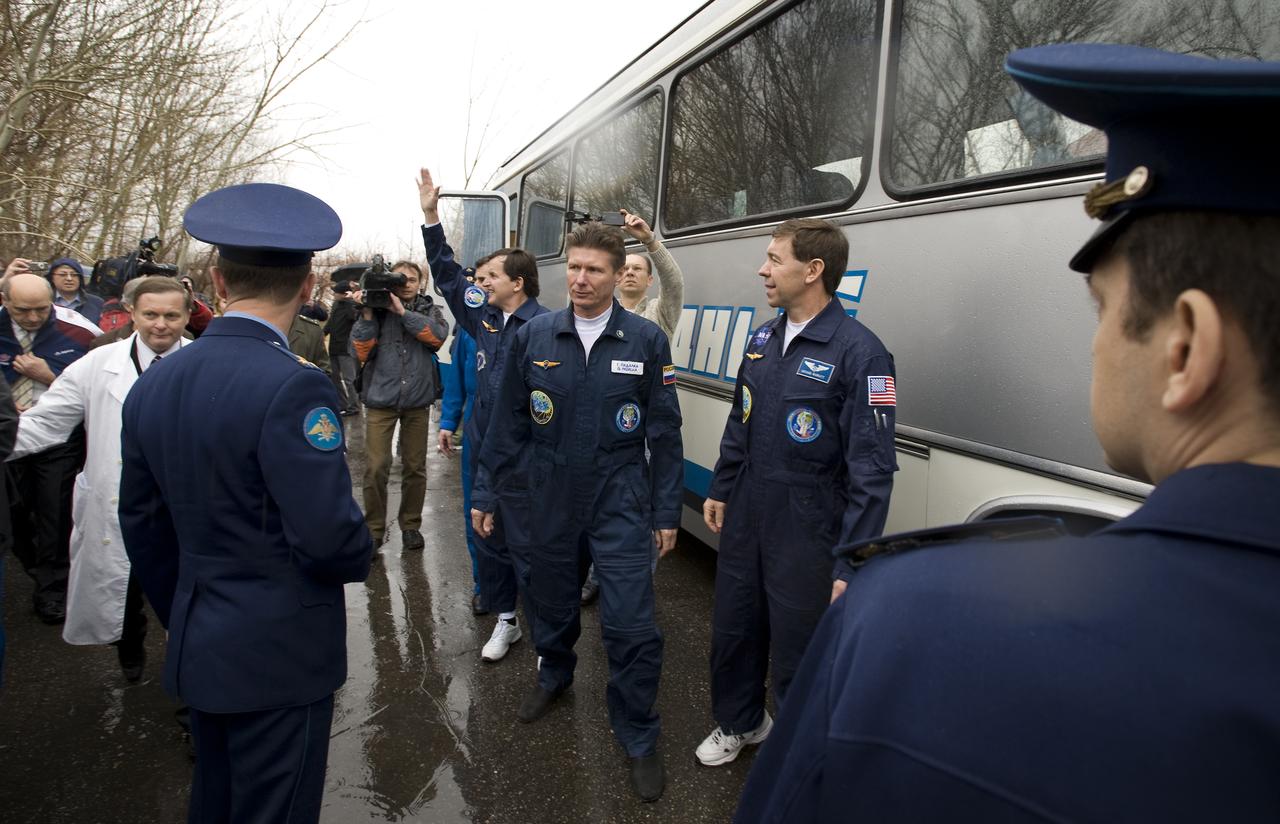 Spaceflight Participant Charles Simonyi, waving on left, Expedition 19 Commander Gennady I. Padalka, center, and Flight Engineer Michael R. Barratt depart the Cosmonaut hotel and board the bus that will take them to building 254 in preparation for their Soyuz launch to the International Space Station on Thursday, March 26, 2009 in Baikonur, Kazakhstan. (Photo Credit: NASA/Bill Ingalls)