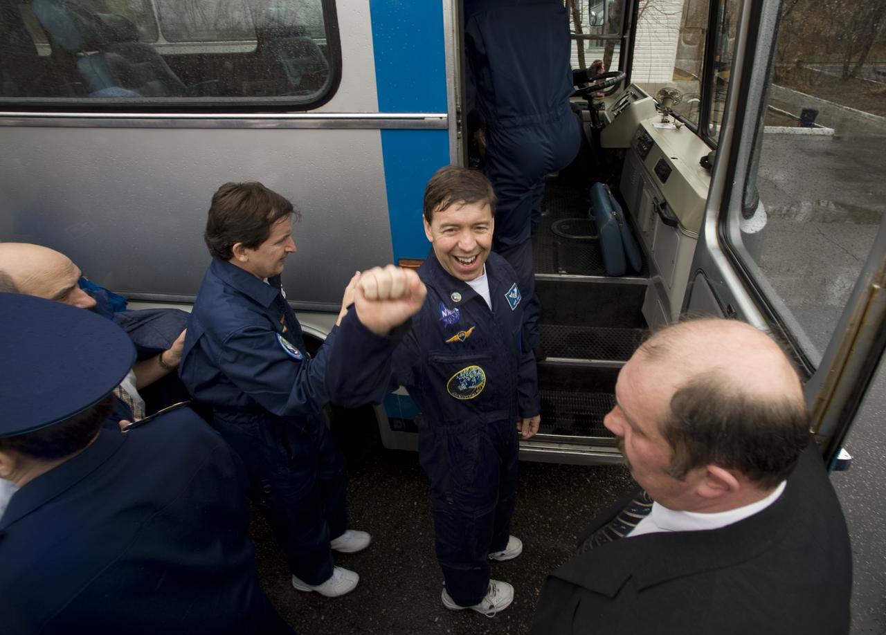 Expedition 19 Flight Engineer Michael R. Barratt raises his arm to the crowd of well wishers as he and Spaceflight Participant Charles Simonyi, left, and Commander Gennady I. Padalka depart the Cosmonaut hotel and board the bus that will take them to building 254 in preparation for their Soyuz launch to the International Space Station on Thursday, March 26, 2009 in Baikonur, Kazakhstan. (Photo Credit: NASA/Bill Ingalls)