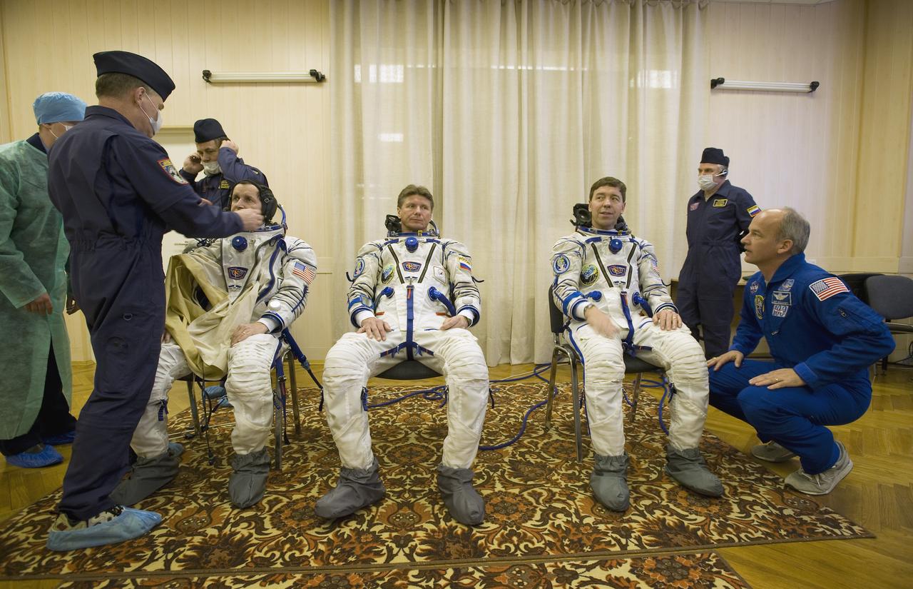 Spaceflight Participant Charles Simonyi, left, Expedition 19 Commander Gennady I. Padalka, center, and Flight Engineer Michael R. Barratt don their Russian Sokol suits in preparation for their Soyuz launch to the International Space Station on Thursday, March 26, 2009 in Baikonur, Kazakhstan. (Photo Credit: NASA/Bill Ingalls)