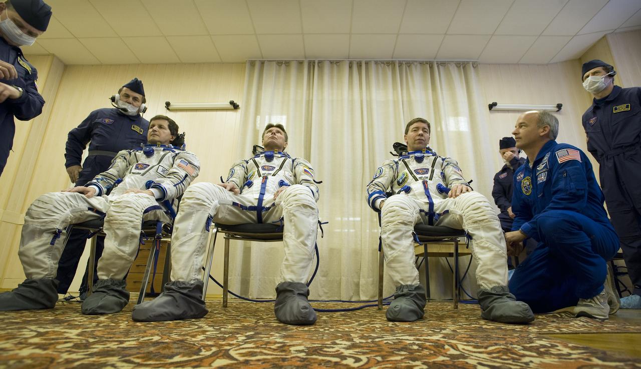 Spaceflight Participant Charles Simonyi, left, Expedition 19 Commander Gennady I. Padalka, center, and Flight Engineer Michael R. Barratt don their Russian Sokol suits in preparation for their Soyuz launch to the International Space Station on Thursday, March 26, 2009 in Baikonur, Kazakhstan. (Photo Credit: NASA/Bill Ingalls)