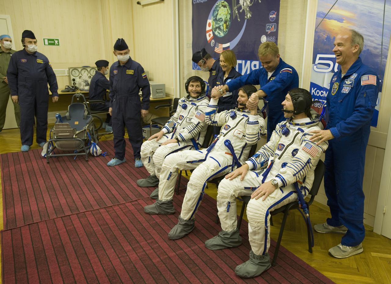 Spaceflight Participant Charles Simonyi, seated left, Expedition 19 Commander Gennady I. Padalka, seated center, Flight Engineer Michael R. Barratt, seated right, backup spaceflight participant Esther Dyson, standing left, backup Expedition 19 flight engineer Maxim Suraev, standing center, and backup commander Jeffrey Williams are seen in the suit up room at building 254 on Thursday, March 26, 2009 in Baikonur, Kazakhstan. Photo Credit: (NASA/Bill Ingalls)