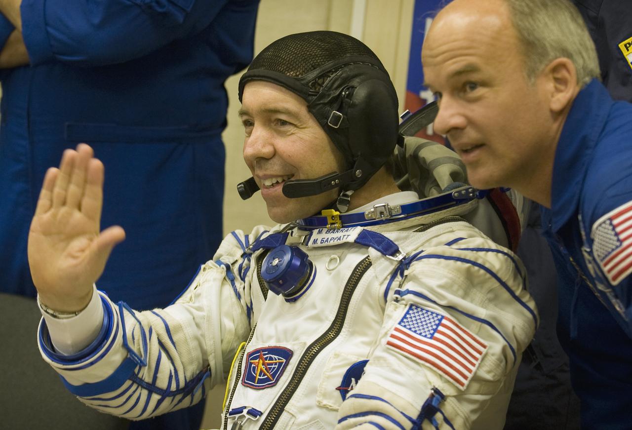 Expedition 19 Flight Engineer Michael R. Barratt, left, waves hello to family and colleagues with backup commander Jeffrey Williams in the suit up room of building 254, Thursday, March 26, 2009 in Baikonur, Kazakhstan. (Photo Credit: NASA/Bill Ingalls)