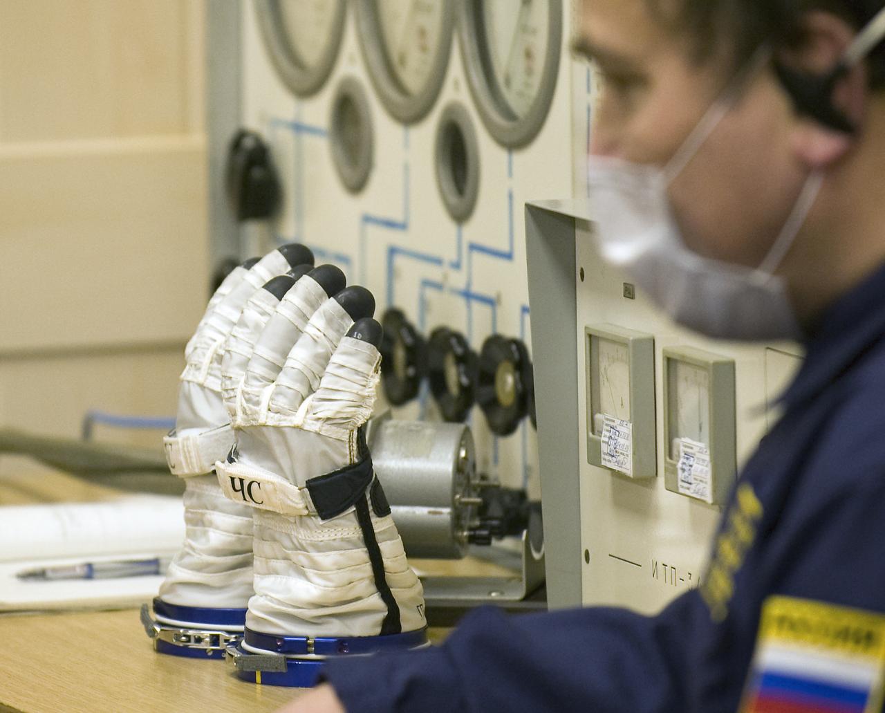 Expedition 19 Flight Engineer Michael R. Barratt's Russian Sokol suit gloves are ready for him to wear during the pressure check procedure prior to the Soyuz launch to the International Space Station with Commander Gennady I. Padalka and Spaceflight Participant Charles Simonyi on Thursday, March 26, 2009 in Baikonur, Kazakhstan. (Photo Credit: NASA/Bill Ingalls)