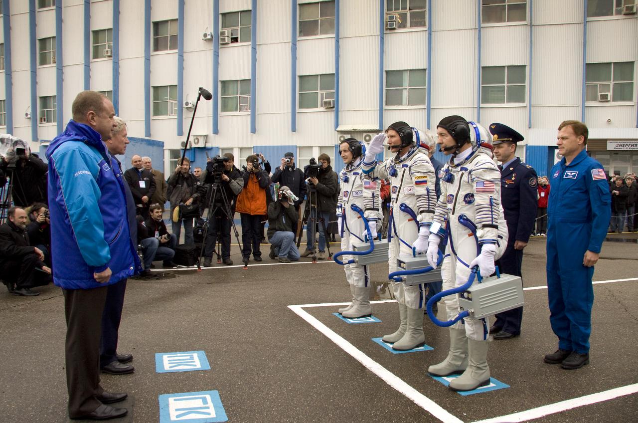 Spaceflight Participant Charles Simonyi, left, Expedition 19 Commander Gennady I. Padalka, center, and Flight Engineer Michael R. Barratt salute officials prior to boarding the bus that will take them to the Soyuz launch pad on Thursday, March 26, 2009 in Baikonur, Kazakhstan.  Photo Credit:  NASA/Victor Zelentsov)