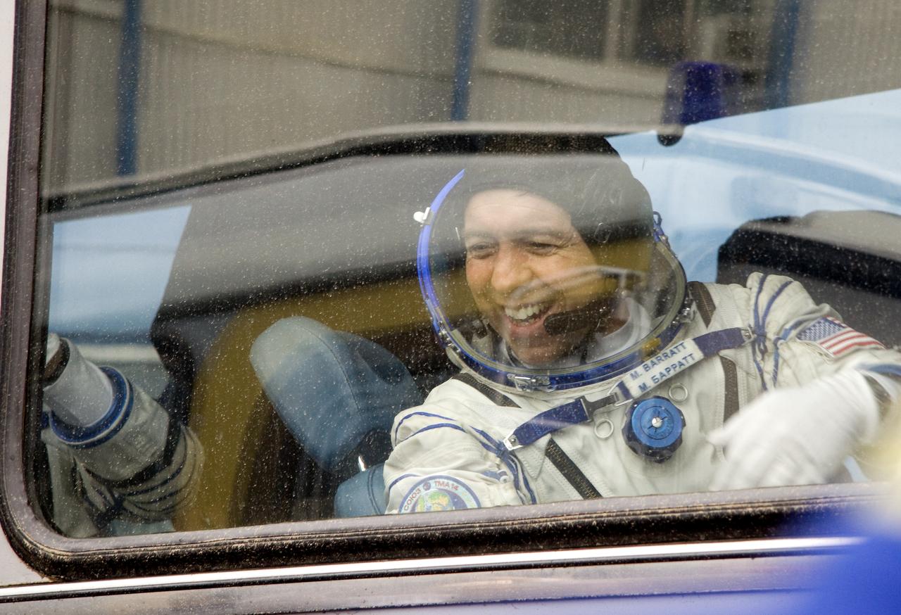 Expedition 19 Flight Engineer Michael R. Barratt waves goodbye to his family from the bus that will take him, Expedition 19 Commander Gennady I. Padalka and Spaceflight Participant Charles Simonyi to the Soyuz launch pad on Thursday, March 26, 2009 in Baikonur, Kazakhstan.  Photo Credit: NASA/Victor Zelentsov)