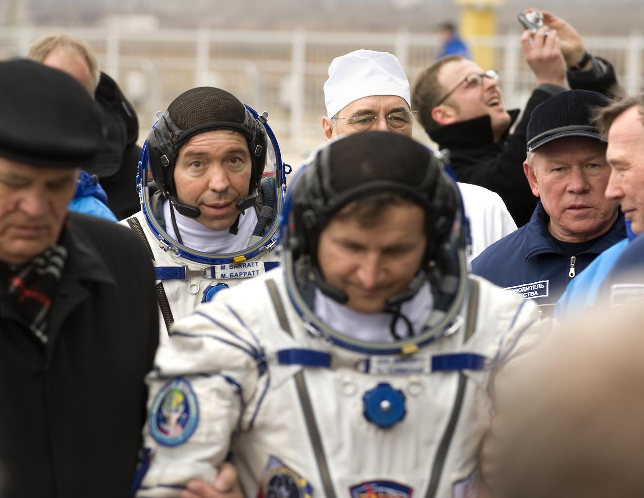 Expedition 19 Flight Engineer Michael R. Barratt, background, and Spaceflight Participant Charles Simonyi walk with Expedition 19 Commander Gennady I. Padalka to the base of the Soyuz rocket prior to launch on Thursday, March 26, 2009 in Baikonur, Kazakhstan. (Photo Credit: NASA/Bill Ingalls)