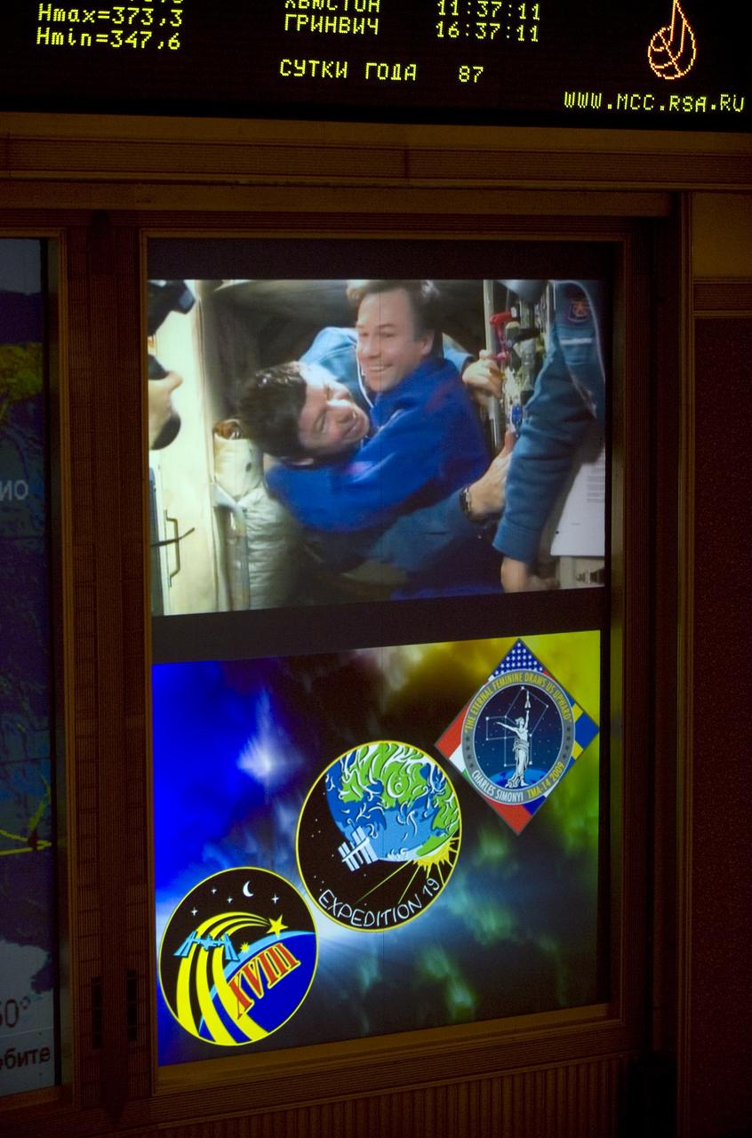 A large TV screen in Russian Mission Control Center in Korolev, Russia shows Cosmonaut Yury Lonchakov, right, welcoming Expedition 19 Flight Engineer Michael R. Barratt onboard the International Space Station after he fellow crew members Expedition 19 Commander Gennady I. Padalka and Spaceflight Participant Charles Simonyi docked their Soyuz TMA-14 spacecraft on Saturday, March 28, 2009. Photo Credit: (NASA/Bill Ingalls)