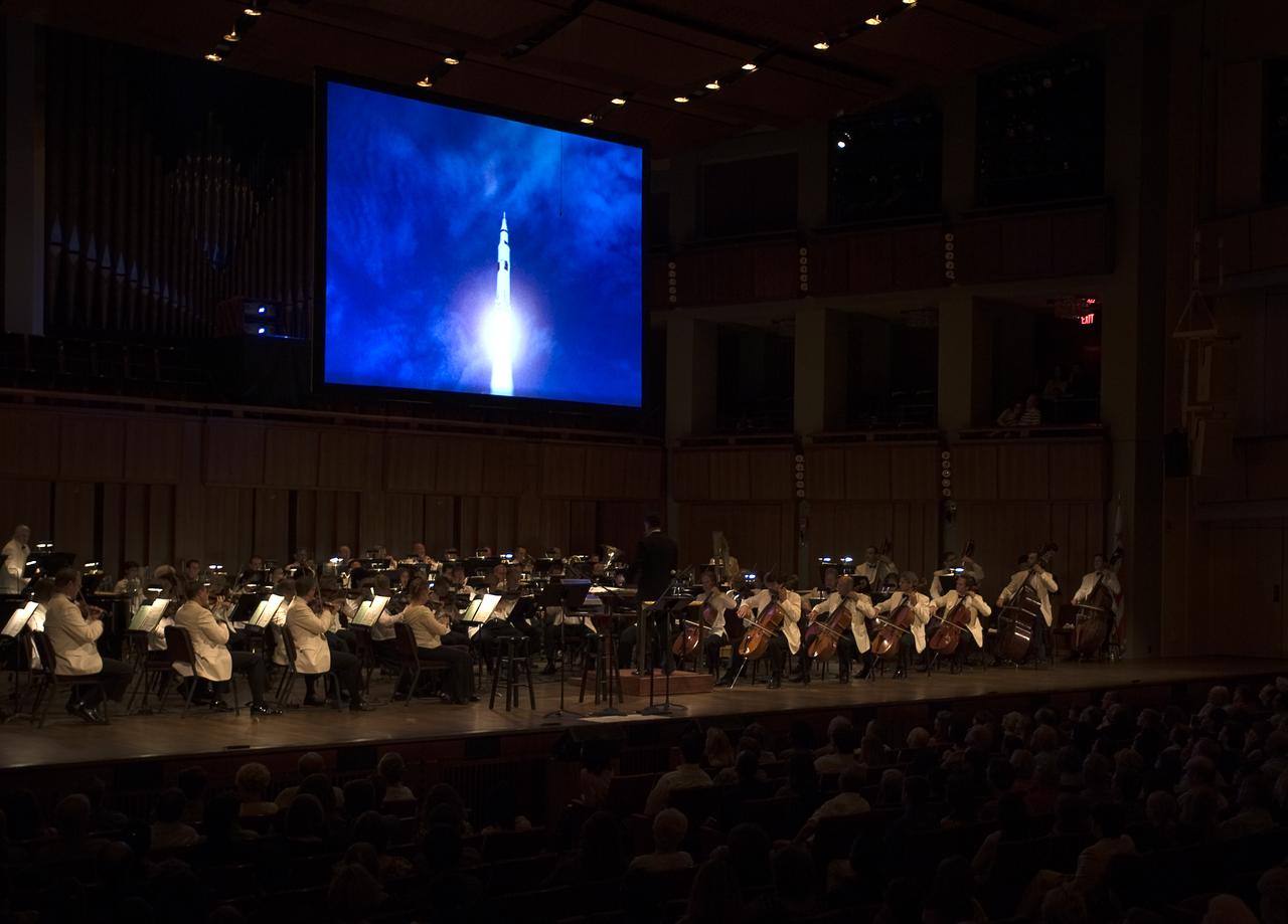 Video footage of an Apollo launch is projected on a screen above the National Symphony Orchestra, under the baton of Emil de Cou, during the "Salute to Apollo" ceremony at the Kennedy Center for the Performing Arts, Saturday, July 18, 2009 in Washington. The event was part of NASA's week long celebration of the Apollo 40th Anniversary. Photo Credit: (NASA/Bill Ingalls)