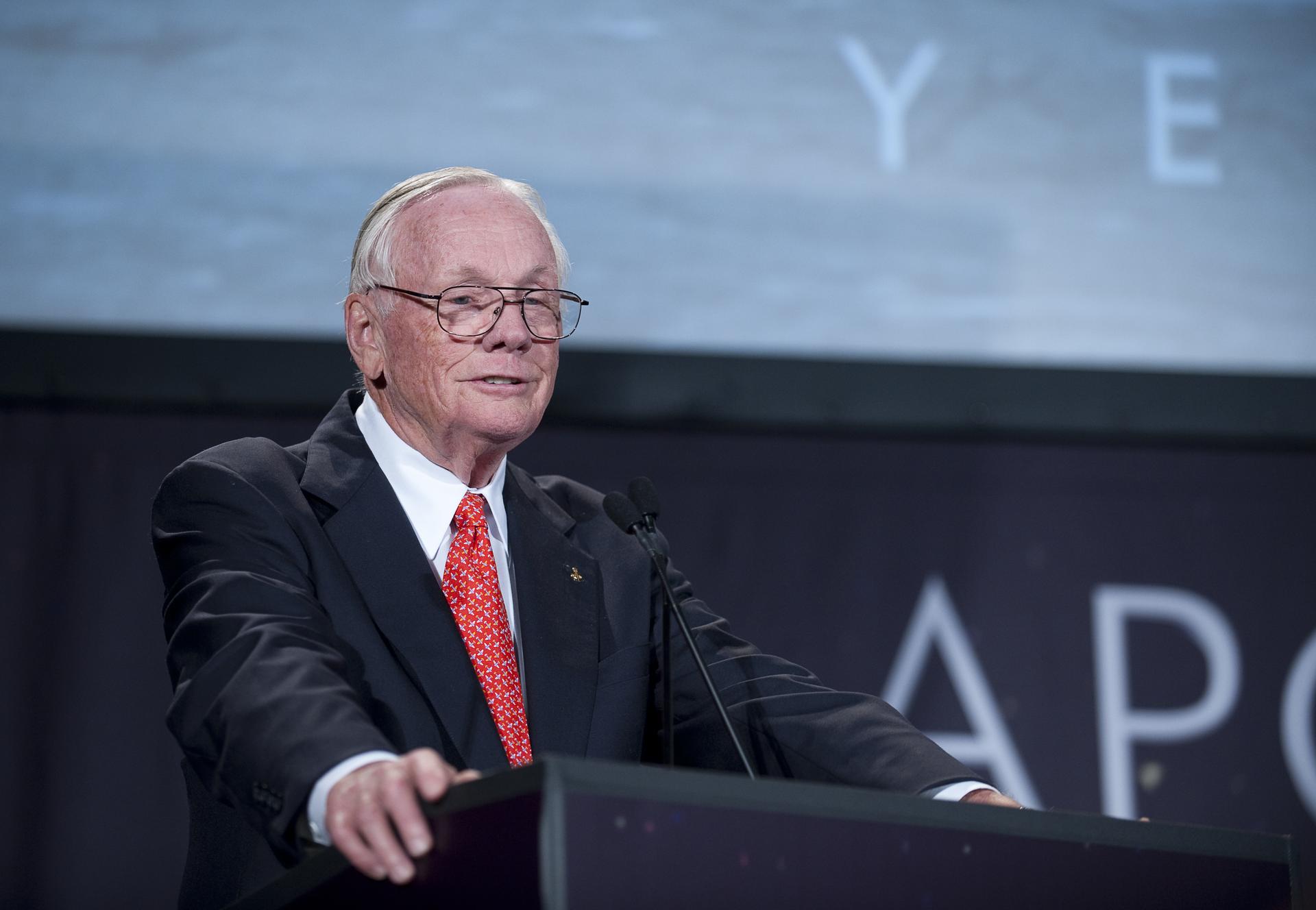 Neil Armstrong stand at a podium while speaking during a Apollo 40th anniversary celebration.