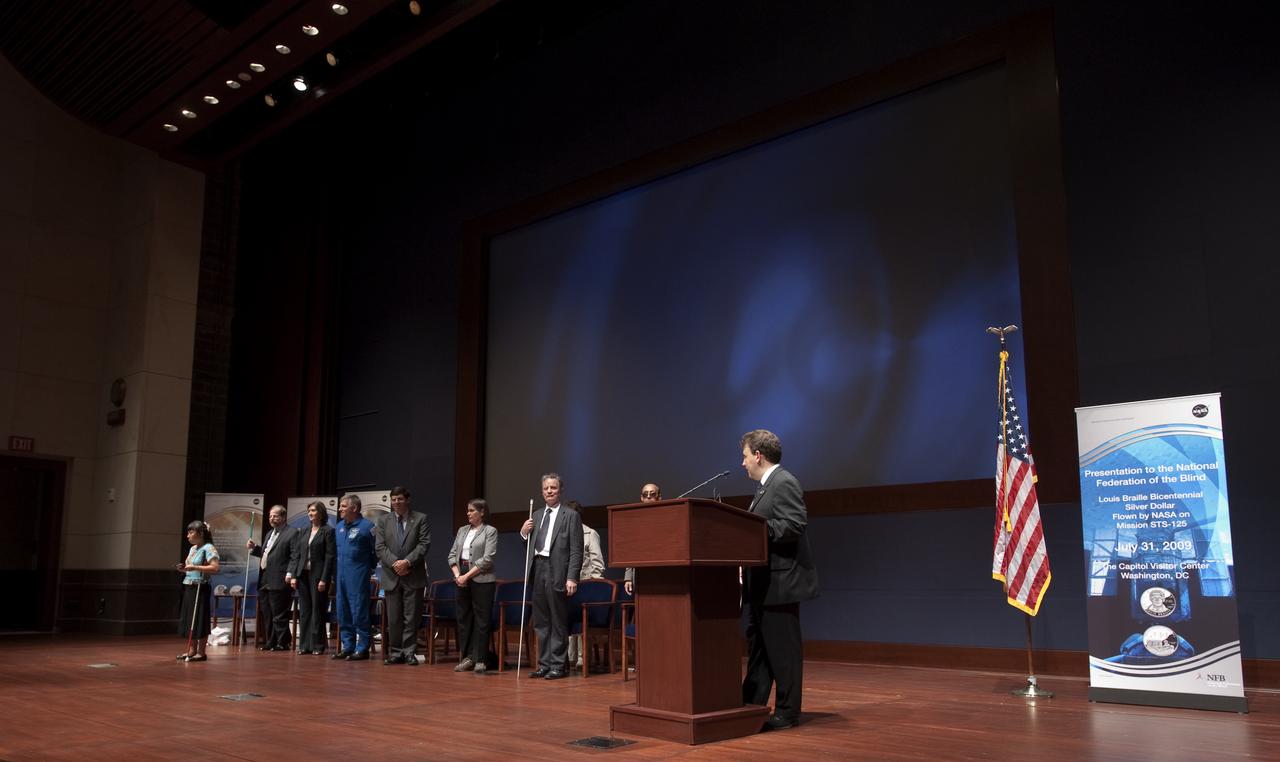 Mark Riccobono, executive director of the Jernigan Institute of the National Federation of the Blind, at podium, delivers remarks at a ceremony where senior NASA officials presented the NFB with two Louis Braille Bicentennial Silver Dollars that flew on Space Shuttle Atlantis' mission (STS-125) to the Hubble Space Telescope in May 2009, Friday evening, July 31, 2009, at the Capitol Visitors Center in Washington. Photo Credit: (NASA/Paul E. Alers)