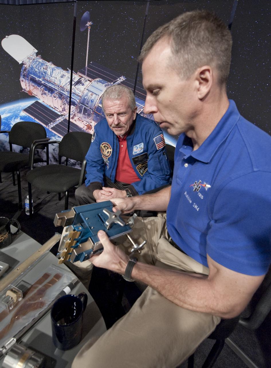 STS-125 Mission Specialist Andrew Feustel, right, shows a part from the Hubble Space Telescope to retired astronaut Loren Shriver, who flew on the Hubble deployment mission STS-31 in 1990, following a press conference, Wednesday, Sept. 9, 2009, after astronomers declared the telescope a fully rejuvenated observatory with the release Wednesday of observations from four of its six operating science instruments at NASA Headquarters in Washington. Photo Credit: (NASA/Paul E. Alers)