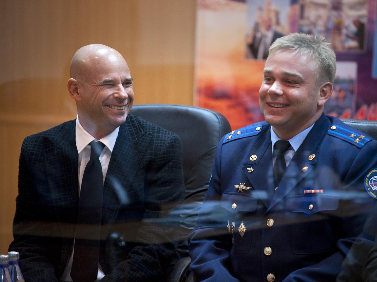 Spaceflight Participant Guy Laliberté, left, and Expedition 21 Flight Engineer Maxim Suraev smile and laugh during the State Commission meeting to approve the Soyuz launch of Expedition 21 Flight Engineer Jeffrey N. Williams, Expedition 21 Flight Engineer Maxim Suraev, and Spaceflight Participant Guy Laliberté on Tuesday, Sept. 29, 2009 in Baikonur, Kazakhstan. The crew is kept in a separate room with a glass window in order to help maintain their health. Photo Credit: (NASA/Bill Ingalls)