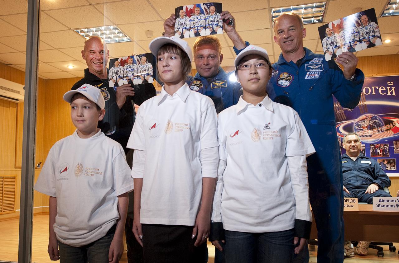 Spaceflight Participant Guy Laliberté, back left, Expedition 21 Flight Engineer Maxim Suraev, back center, Expedition 21 Flight Engineer Jeffrey N. Williams, back right, pose for a photograph with winners of a ROSCOSMOS drawing contest, Oleg Golovin, from Elektrostal, Russia, front left, Nastya Mestyashova from Orenburg, Russia, front center, and Dong Yue from China at the start of the press conference, Tuesday, Sept. 29, 2009 at the Cosmonaut Hotel in Baikonur, Kazakhstan. Their winning drawings will be incorporated into the Expedition 22 mission patch. Photo Credit: (NASA/Bill Ingalls)