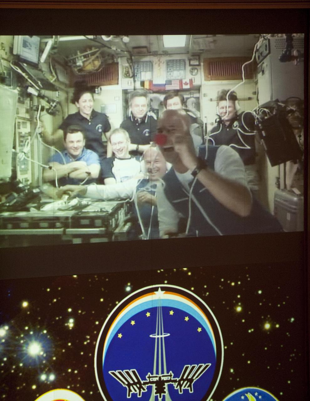 Spaceflight Participant Guy Laliberté is in the foreground as the entire crew onboard the International Space Station (ISS) is seen on a screen in the Mission Control Center Moscow in Korolev, Russia shortly after the successful docking of the Soyuz TMA-16 spacecraft with the International Space Station marking the start of Expedition 21 with Flight Engineer Jeffrey N. Williams, Expedition 21 Flight Engineer Maxim Suraev, and Spaceflight Participant Guy Laliberté, Friday, Oct. 2, 2009. Photo Credit: (NASA/Bill Ingalls)