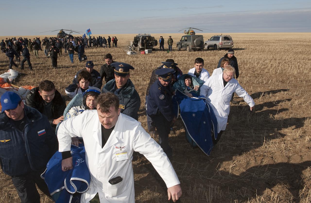 Expedition 20 Flight Engineer Michael Barratt, left, and Expedition 20 Commander Gennady Padalka, right, are carried in chairs to the medical tent shortly after they and Spaceflight participant Guy Laliberté landed in their Soyuz TMA-14 capsule near the town of Arkalyk, Kazakhstan on Sunday, Oct. 11, 2009. Padalka and Barratt are returning from six months onboard the International Space Station, along with Laliberté who arrived at the station on Oct. 2 with Expedition 21 Flight Engineers Jeff Williams and Maxim Suraev aboard the Soyuz TMA-16 spacecraft.  Photo Credit: (NASA/Bill Ingalls)