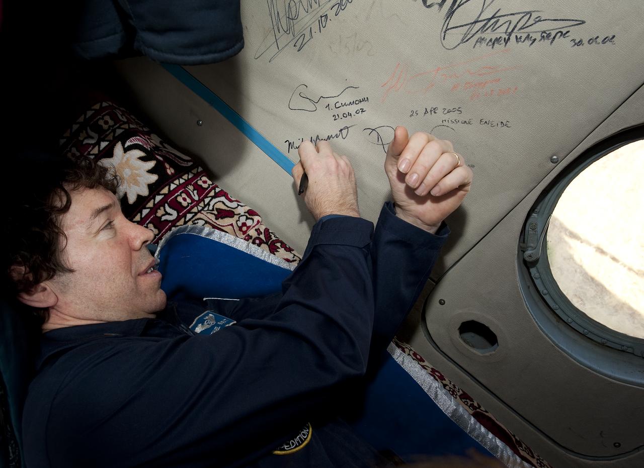 Expedition 20 Flight Engineer Michael Barratt signs the inside of his helicopter shortly after shortly after he and Expedition 20 Commander Gennady Padalka, and spaceflight participant Guy Laliberté landed their Soyuz TMA-14 capsule near the town of Arkalyk, Kazakhstan on Sunday, Oct. 11, 2009. Padalka and Barratt are returning from six months onboard the International Space Station, along with Laliberté who arrived at the station on Oct. 2 with Expedition 21 Flight Engineers Jeff Williams and Maxim Suraev aboard the Soyuz TMA-16 spacecraft.  Photo Credit: (NASA/Bill Ingalls)