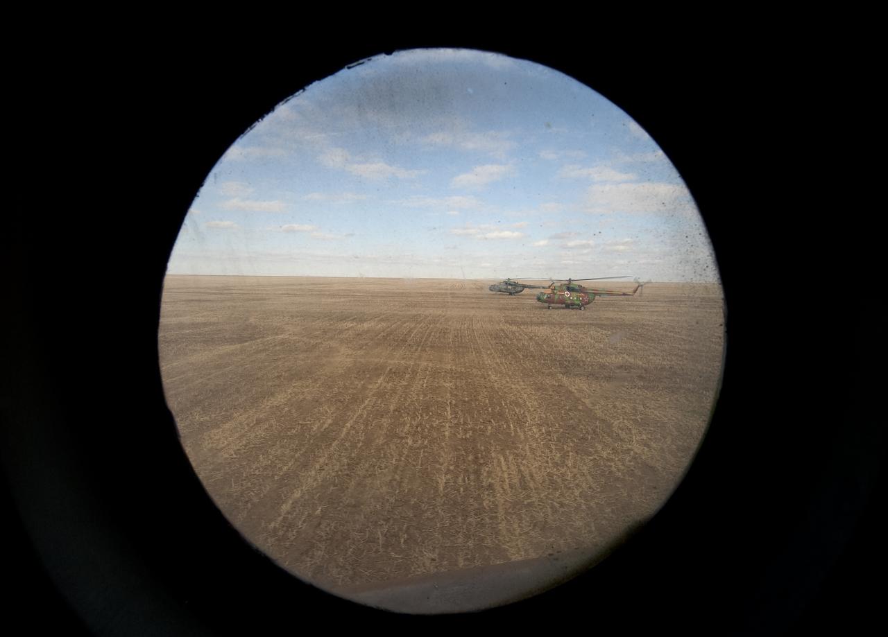 Russian Search and Rescue helicopters are seen out the window of another helicopter carrying Expedition 20 Flight Engineer Michael Barratt shortly after shortly after he and Expedition 20 Commander Gennady Padalka, and spaceflight participant Guy Laliberté landed their Soyuz TMA-14 capsule near the town of Arkalyk, Kazakhstan on Sunday, Oct. 11, 2009. Padalka and Barratt are returning from six months onboard the International Space Station, along with Laliberté who arrived at the station on Oct. 2 with Expedition 21 Flight Engineers Jeff Williams and Maxim Suraev aboard the Soyuz TMA-16 spacecraft. Photo Credit: (NASA/Bill Ingalls)