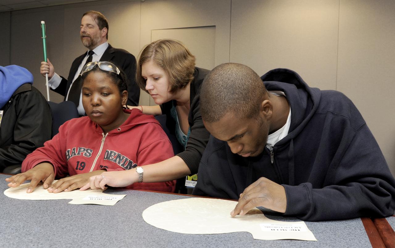 Maryland School for the Blind students Andrea Washington, left, and Derontay Taylor, right, along with science teacher Colleen Shovestull, center, use their sense of touch on topographical maps to learn about the Moon during a visit to NASA Headquarters in Washington, Thursday, Oct. 29, 2009.  Seven students from the Maryland School for the Blind visited NASA and participated in activities to learn about NASA'smission, functions, and careers. Photo Credit: (NASA/Paul E. Alers)