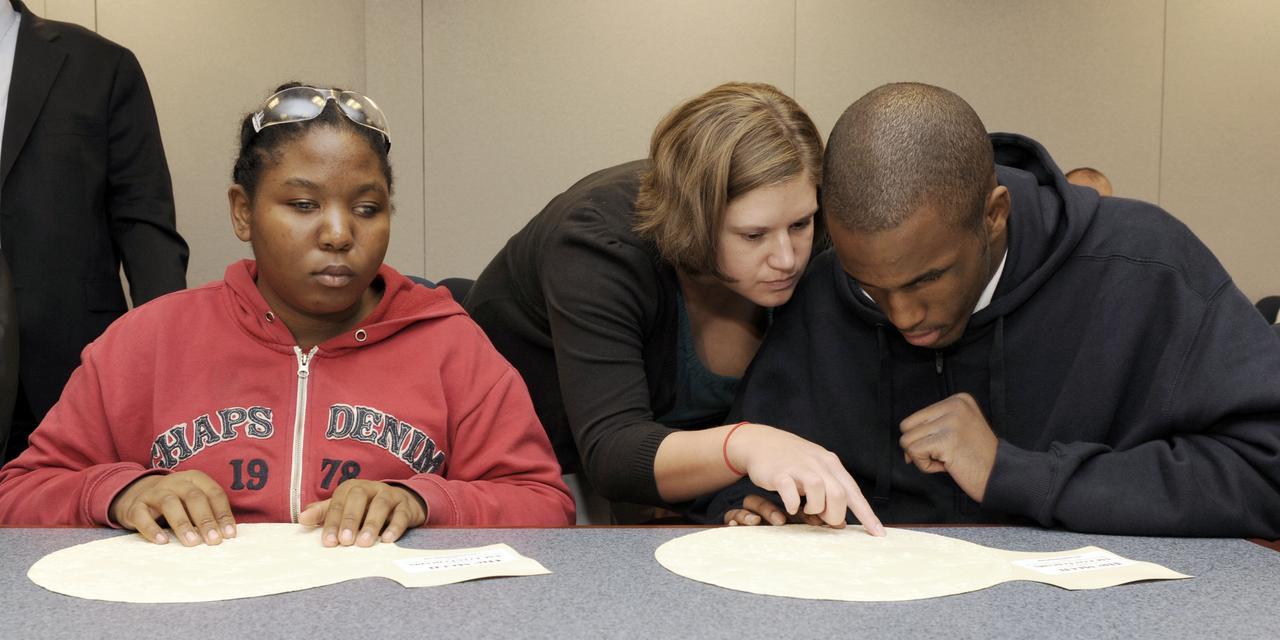 Maryland School for the Blind students Andrea Washington, left, and Derontay Taylor, right, along with science teacher Colleen Shovestull, center, use their sense of touch on topographical maps to learn about the Moon during a visit to NASA Headquarters in Washington, Thursday, Oct. 29, 2009.  Seven students from the Maryland School for the Blind visited NASA and participated in activities to learn about NASA'smission, functions, and careers. Photo Credit: (NASA/Paul E. Alers)