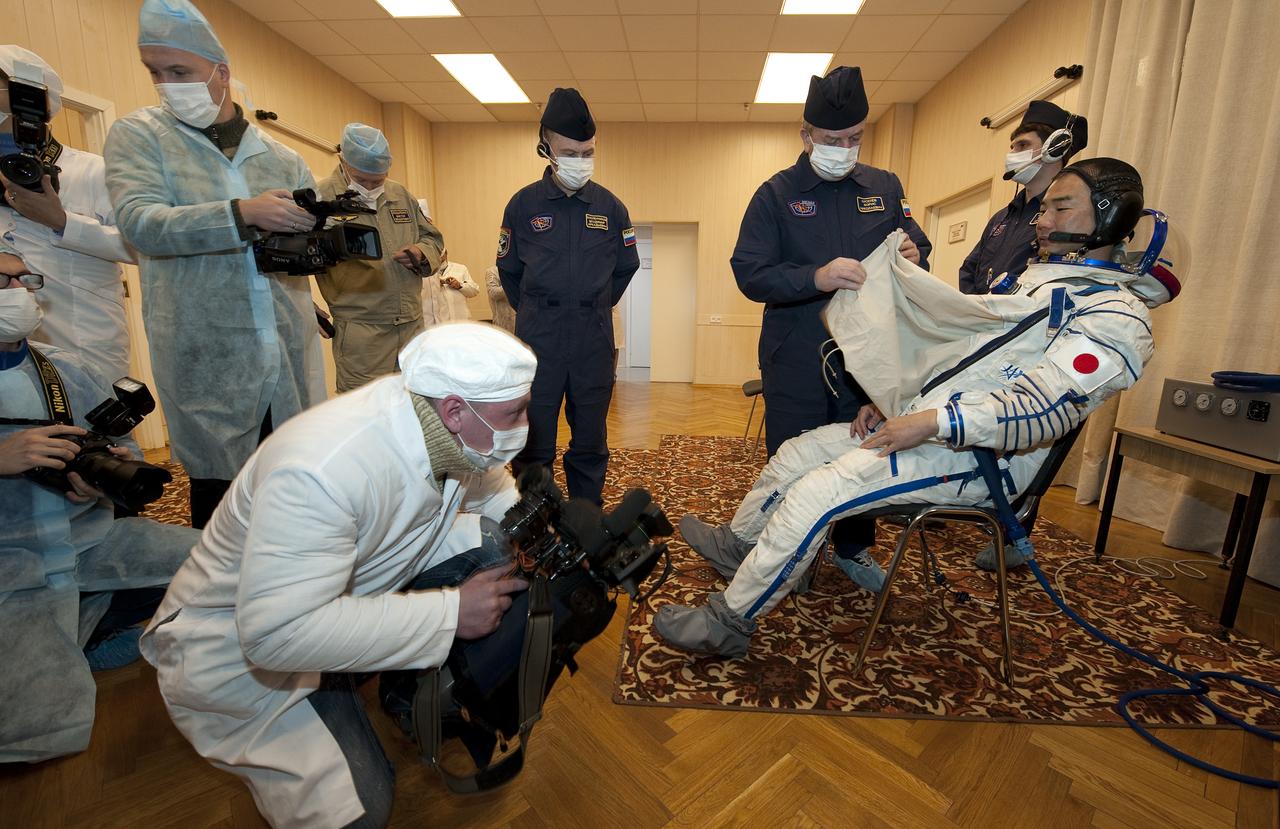 Expedition 22 Flight Engineer Soichi Noguchi of Japan has his Russian Sokol suit prepared for launch by a technician while space agency photographers document the process at the Baikonur Cosmodrome in Baikonur, Kazakhstan, Sunday, Dec. 20, 2009. Soichi and fellow Expedition 22 crew members NASA Flight Engineer Timothy J. Creamer of the U.S., Soyuz Commander Oleg Kotov of Russia launched in their Soyuz TMA-17 rocket from the Baikonur Cosmodrome in Kazakhstan on Monday, Dec. 21, 2009. (Photo Credit: NASA/Bill Ingalls)