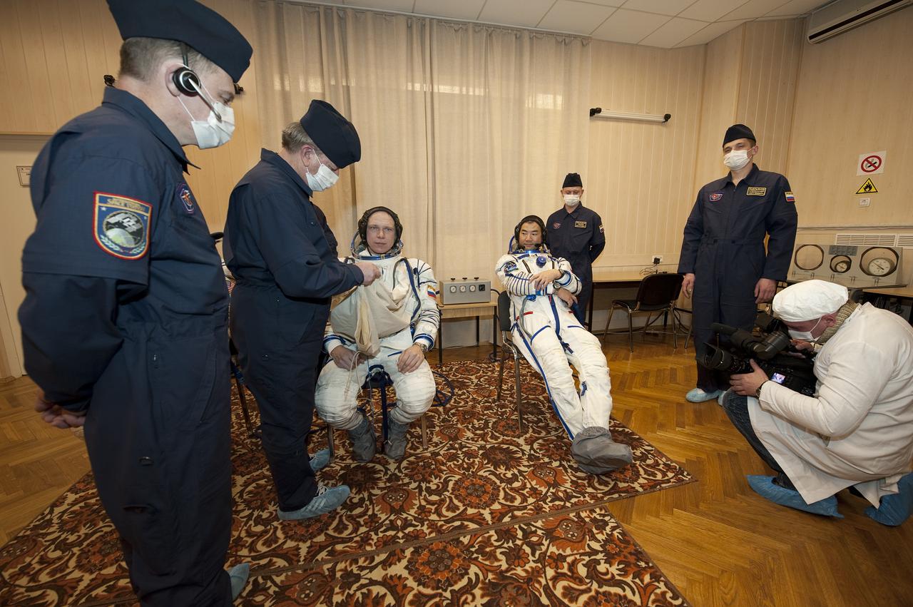 Expedition 22 Soyuz Commander Oleg Kotov of Russia, seated left, dons his Russian Sokol as Flight Engineer Soichi Noguchi of Japan, seated right, looks on at the Baikonur Cosmodrome in Baikonur, Kazakhstan, Sunday, Dec. 20, 2009. Kotov, Noguchi and NASA Flight Engineer Timothy J. Creamer of the U.S. launched in their Soyuz TMA-17 rocket from the Baikonur Cosmodrome in Kazakhstan on Monday, Dec. 21, 2009. (Photo Credit: NASA/Bill Ingalls)