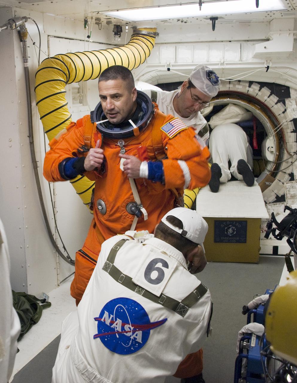CAPE CANAVERAL, Fla. - In the White Room at Launch Pad 39A on NASA's Kennedy Space Center in Florida, United Space Alliance suit technicians and NASA quality inspectors ensure the proper fit of the launch-and-entry suit of STS-130 Commander George Zamka as he prepares to enter space shuttle Endeavour for launch.  This is the second launch attempt for space shuttle Endeavour's STS-130 crew.  The first attempt on Feb. 7 was scrubbed due to unfavorable weather. The primary payload for the STS-130 mission to the International Space Station is the Tranquility node, a pressurized module that will provide additional room for crew members and many of the station's life support and environmental control systems. Attached to one end of Tranquility is a cupola, a unique work area with six windows on its sides and one on top.  The cupola resembles a circular bay window and will provide a vastly improved view of the station's exterior. The multi-directional view will allow the crew to monitor spacewalks and docking operations, as well as provide a spectacular view of Earth and other celestial objects. The module was built in Turin, Italy, by Thales Alenia Space for the European Space Agency.  Endeavour's launch is set for Feb. 8 at 4:14 a.m. EST.  For information on the STS-130 mission and crew, visit http:__www.nasa.gov_mission_pages_shuttle_shuttlemissions_sts130_index.html.  Photo credit: NASA_Sandra Joseph and Kevin O'Connell