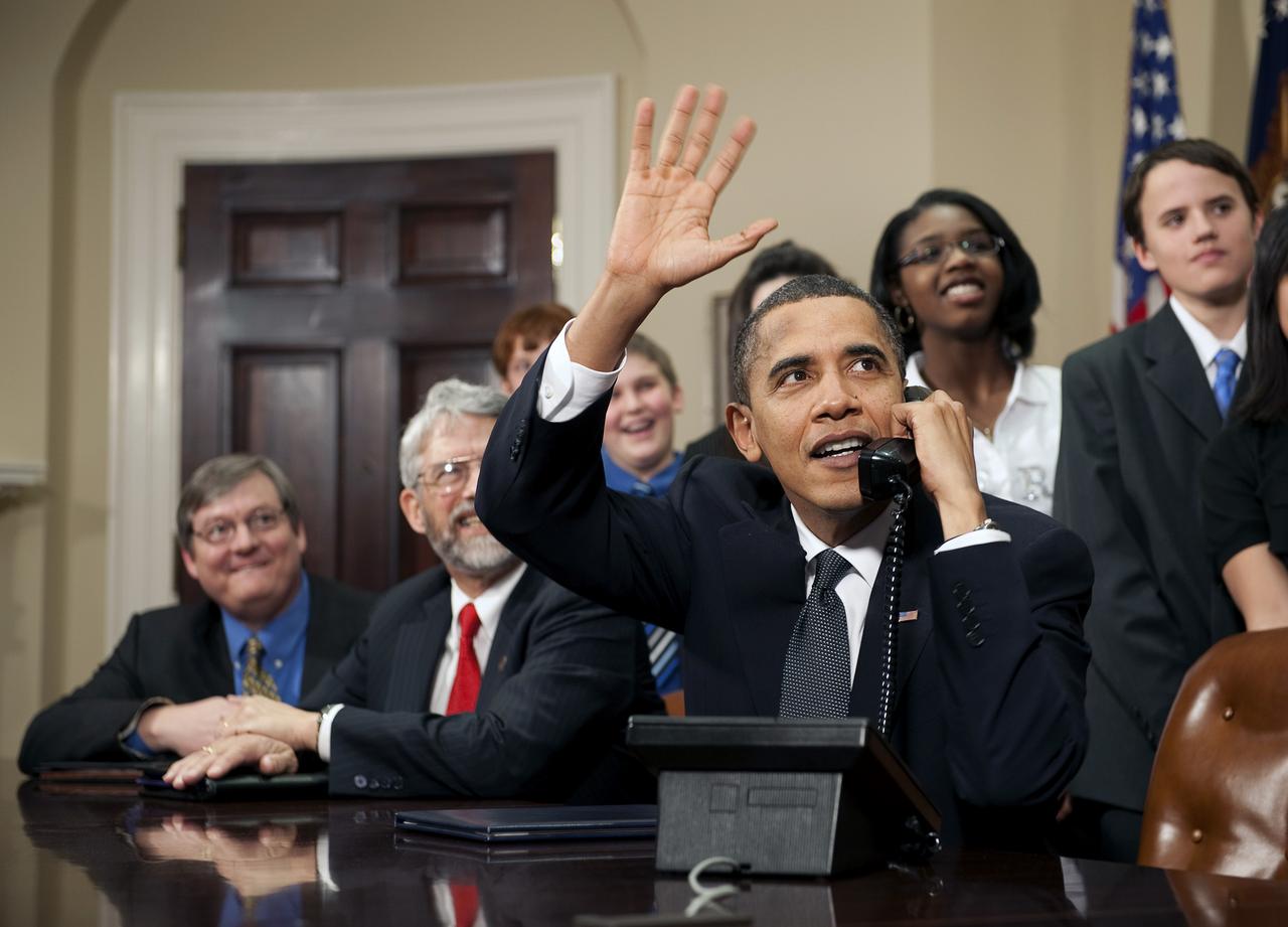 U.S. President Barack Obama, accompanied by members of Congress and middle school children,  waves as he talks on the phone from the Roosevelt Room of the White House to astronauts on the International Space Station, Wednesday, Feb. 17, 2010 in Washington. Photo Credit: (NASA/Bill Ingalls)