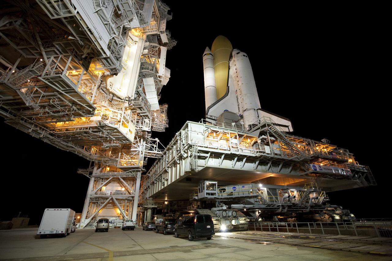 CAPE CANAVERAL, Fla. – A crawler-transporter delivers space shuttle Discovery over the flame trench next to the fixed service structure on Launch Pad 39A at NASA's Kennedy Space Center in Florida before sunrise. Discovery's first motion on its 3.4-mile trip from the Vehicle Assembly Building was at 11:58 p.m. EST March 2. The shuttle was secured on the pad at 6:48 a.m. March 3. Rollout is a significant milestone in launch processing activities. The seven-member STS-131 crew will deliver the multi-purpose logistics module Leonardo, filled with resupply stowage platforms and racks, to the International Space Station aboard Discovery. Targeted for launch on April 5, STS-131 will be the 33rd shuttle mission to the station and the 131st shuttle mission overall. For information on the STS-131 mission and crew, visit http:__www.nasa.gov_mission_pages_shuttle_shuttlemissions_sts131_index.html. Photo credit: NASA_Amanda Diller