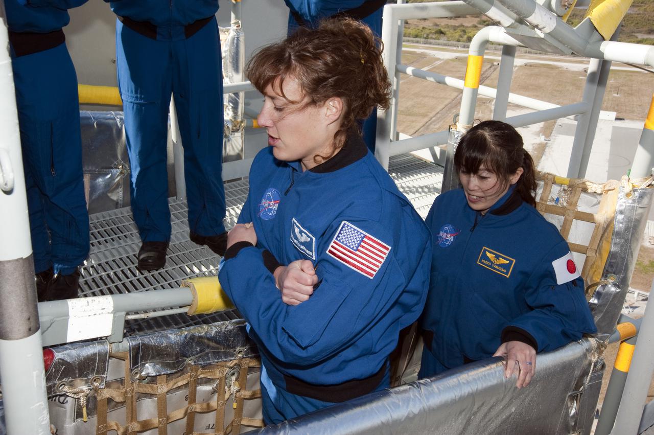 CAPE CANAVERAL, Fla. - On a brisk Florida morning at Launch Pad 39A at NASA's Kennedy Space Center, STS-131 Mission Specialists Dorothy Metcalf-Lindenburger, left, and Naoko Yamazaki of the Japan Aerospace Exploration Agency try out one of the slidewire baskets during training on the emergency exit system at the pad. The system includes seven baskets suspended from seven slidewires that extend from the fixed service structure to a landing zone 1,200 feet west of the pad.  The crew members of space shuttle Discovery's STS-131 mission are at Kennedy for training related to their launch dress rehearsal, the Terminal Countdown Demonstration Test.  The seven-member crew will deliver the multi-purpose logistics module Leonardo, filled with resupply stowage platforms and racks, to the International Space Station aboard Discovery. Targeted for launch on April 5, STS-131 will be the 33rd shuttle mission to the station and the 131st shuttle mission overall. For information on the STS-131 mission and crew, visit http:__www.nasa.gov_mission_pages_shuttle_shuttlemissions_sts131_index.html. Photo credit: NASA_Kim Shiflett