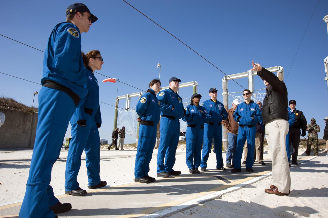 CAPE CANAVERAL, Fla. - On Launch Pad 39A at NASA's Kennedy Space Center in Florida, the members of space shuttle Discovery's STS-131 crew receive further training on the pad's emergency exit system by the catch nets for the slidewire baskets at the base of the pad.  The emergency exit system includes seven baskets suspended from seven slidewires that extend from the fixed service structure to a landing zone 1,200 feet west of the pad.  From left, in the blue flight suits, are Mission Specialists Rick Mastracchio, Dorothy Metcalf-Lindenburger, and Naoko Yamazaki of the Japan Aerospace Exploration Agency; Commander Alan Poindexter; Mission Specialists Stephanie Wilson and Clayton Anderson; and Pilot James P. Dutton Jr.  The crew members of space shuttle Discovery's STS-131 mission are at Kennedy for training related to their launch dress rehearsal, the Terminal Countdown Demonstration Test.  The seven-member crew will deliver the multi-purpose logistics module Leonardo, filled with resupply stowage platforms and racks, to the International Space Station aboard Discovery. Targeted for launch on April 5, STS-131 will be the 33rd shuttle mission to the station and the 131st shuttle mission overall. For information on the STS-131 mission and crew, visit http:__www.nasa.gov_mission_pages_shuttle_shuttlemissions_sts131_index.html. Photo credit: NASA_Kim Shiflett