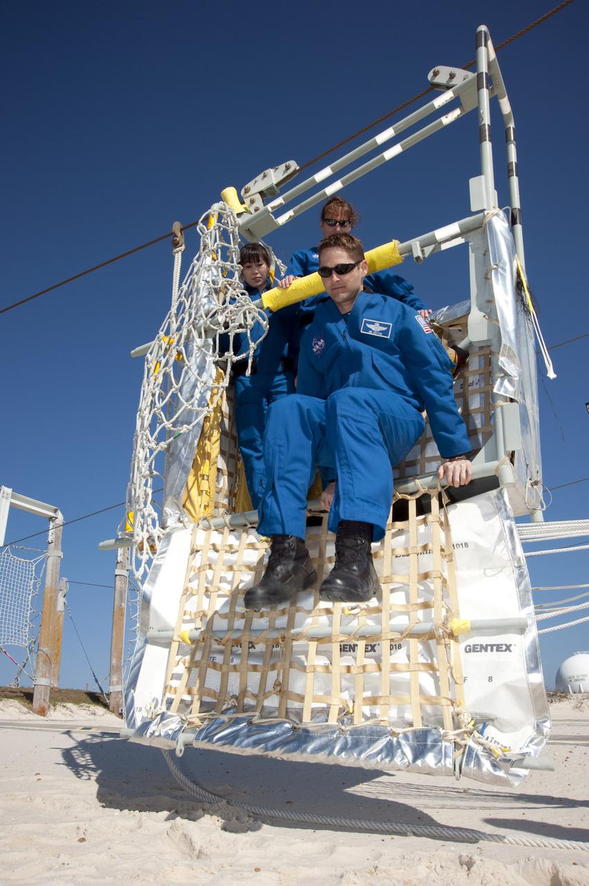 CAPE CANAVERAL, Fla. - At the foot of Launch Pad 39A at NASA's Kennedy Space Center in Florida, STS-131 Pilot James P. Dutton Jr. hops out of a slidewire basket during training on the emergency exit system at the pad.  Looking on are Mission Specialists Naoko Yamazaki of the Japan Aerospace Exploration Agency, at left, and Dorothy Metcalf-Lindenburger.  The system includes seven baskets suspended from seven slidewires that extend from the fixed service structure to a landing zone 1,200 feet west of the pad.  The crew members of space shuttle Discovery's STS-131 mission are at Kennedy for training related to their launch dress rehearsal, the Terminal Countdown Demonstration Test.  The seven-member crew will deliver the multi-purpose logistics module Leonardo, filled with resupply stowage platforms and racks, to the International Space Station aboard Discovery. Targeted for launch on April 5, STS-131 will be the 33rd shuttle mission to the station and the 131st shuttle mission overall. For information on the STS-131 mission and crew, visit http:__www.nasa.gov_mission_pages_shuttle_shuttlemissions_sts131_index.html. Photo credit: NASA_Kim Shiflett