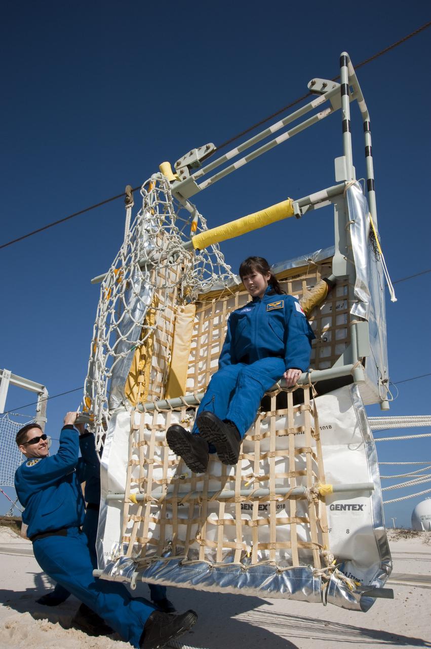 CAPE CANAVERAL, Fla. - At the foot of Launch Pad 39A at NASA's Kennedy Space Center in Florida, STS-131 Mission Specialist Naoko Yamazaki of the Japan Aerospace Exploration Agency hops out of a slidewire basket during training on the emergency exit system at the pad.  Pilot James P. Dutton Jr. holds the basket steady for her.  The system includes seven baskets suspended from seven slidewires that extend from the fixed service structure to a landing zone 1,200 feet west of the pad.  The crew members of space shuttle Discovery's STS-131 mission are at Kennedy for training related to their launch dress rehearsal, the Terminal Countdown Demonstration Test.  The seven-member crew will deliver the multi-purpose logistics module Leonardo, filled with resupply stowage platforms and racks, to the International Space Station aboard Discovery. Targeted for launch on April 5, STS-131 will be the 33rd shuttle mission to the station and the 131st shuttle mission overall. For information on the STS-131 mission and crew, visit http:__www.nasa.gov_mission_pages_shuttle_shuttlemissions_sts131_index.html. Photo credit: NASA_Kim Shiflett
