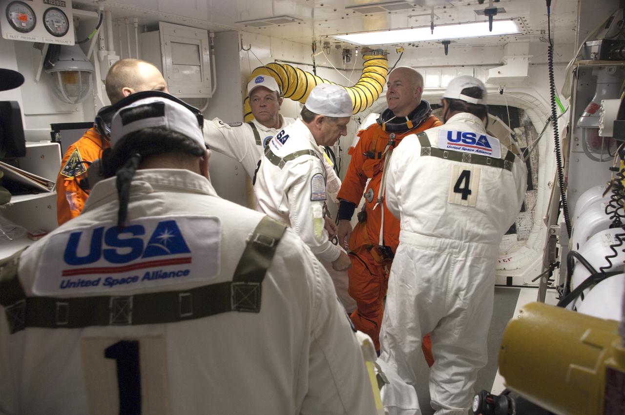 CAPE CANAVERAL, Fla. - At Launch Pad 39A at NASA's Kennedy Space Center in Florida, STS-131 Commander Alan Poindexter, at right in the orange suit, prepares to enter space shuttle Discovery from the pad's White Room.  The members of space shuttle Discovery's STS-131 crew, dressed in their launch-and-entry suits, are participating in the Terminal Countdown Demonstration Test, or TCDT, a dress rehearsal for launch.  TCDT includes training on the emergency exit systems at the launch pad, driving practice of the M-113 armored personnel carrier and a simulated launch countdown. The crew will deliver the multi-purpose logistics module Leonard, filled with resupply stowage platforms and science racks, to the International Space Station. STS-131, targeted for launch on April 5, will be the 33rd shuttle mission to the station and the 131st shuttle mission overall. For information on the STS-131 mission and crew, visit http:__www.nasa.gov_mission_pages_shuttle_shuttlemissions_sts131_index.htm. Photo credit: NASA_Regina Mitchell-Ryall