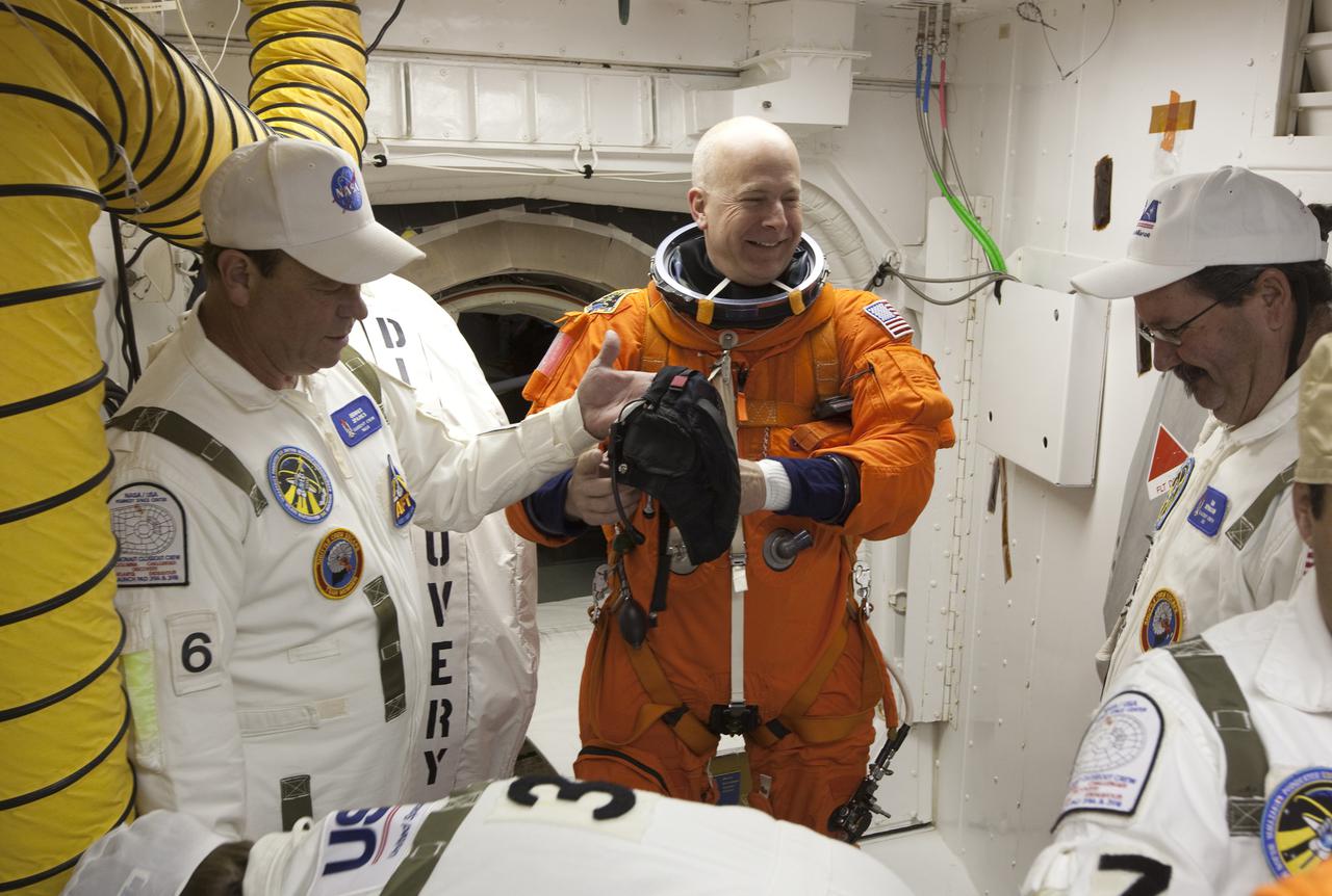 CAPE CANAVERAL, Fla. - At Launch Pad 39A at NASA's Kennedy Space Center in Florida, STS-131 Commander Alan Poindexter, in the orange suit, prepares to enter space shuttle Discovery from the pad's White Room.  The members of space shuttle Discovery's STS-131 crew, dressed in their launch-and-entry suits, are participating in the Terminal Countdown Demonstration Test, or TCDT, a dress rehearsal for launch.  TCDT includes training on the emergency exit systems at the launch pad, driving practice of the M-113 armored personnel carrier and a simulated launch countdown. The crew will deliver the multi-purpose logistics module Leonardo, filled with resupply stowage platforms and science racks, to the International Space Station. STS-131, targeted for launch on April 5, will be the 33rd shuttle mission to the station and the 131st shuttle mission overall. For information on the STS-131 mission and crew, visit http:__www.nasa.gov_mission_pages_shuttle_shuttlemissions_sts131_index.htm. Photo courtesy of Scott Andrews