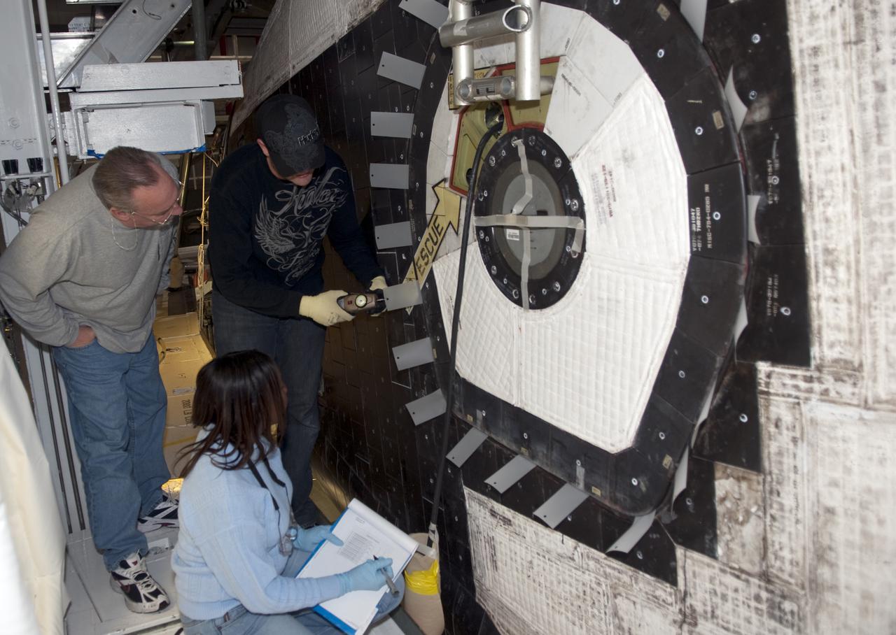 CAPE CANAVERAL, Fla. - Inside Orbiter Processing Facility-1 at Kennedy Space Center in Florida, technicians secure and check shuttle Atlantis’ hatch in preparation for the Mylar Pull Test. During the test, a scale is used to measure the force required to pull a piece of Mylar paper out from between the door and structural wall thermal barriers. The pull test is performed to ensure the integrity of the hatch and that it has closed properly. Atlantis is being processed for the STS-132 mission targeted for launch May 14. The six-member crew will deliver an Integrated Cargo Carrier and a Russian-built Mini Research Module to the International Space Station. Photo credit: NASA_Jim Grossmann