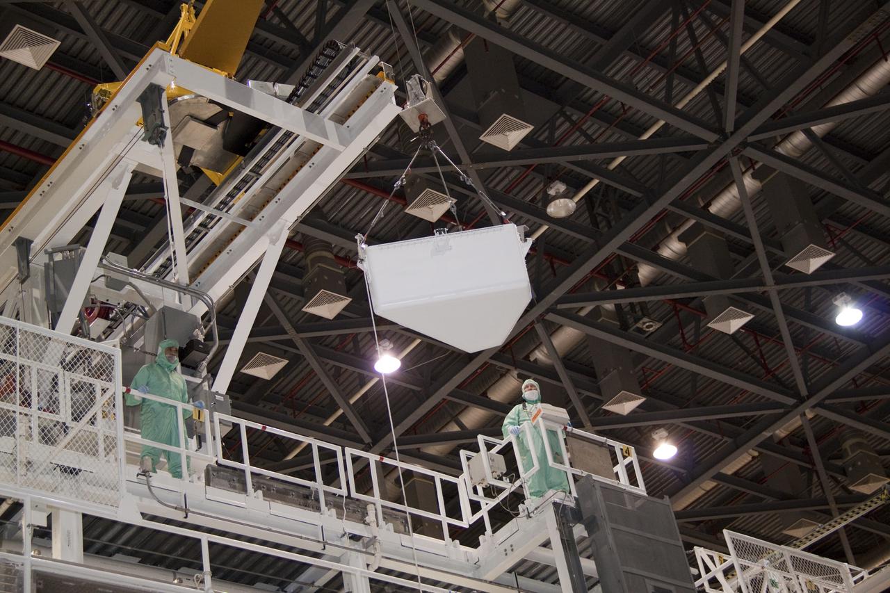 CAPE CANAVERAL, Fla. – In Orbiter Processing Facility-1 at NASA's Kennedy Space Center in Florida, workers dressed in clean room attire, known as bunny suits, monitor the tool stowage assembly as it is lifted by jib crane above the work platform on which they are standing.  The tool box is being installed into space shuttle Atlantis' payload bay.  The assembly contains tools and hardware that will be needed on the extravehicular activities, or spacewalks, conducted during the STS-132 mission. On STS-132, the six-member crew will deliver an Integrated Cargo Carrier and a Russian-built Mini-Research Module to the International Space Station.  STS-132 is the 34th mission to the station and the 132nd space shuttle mission.   Launch is targeted for May 14.  For information on the STS-132 mission, visit http:__www.nasa.gov_mission_pages_shuttle_shuttlemissions_sts132_index.html. Photo credit: NASA_Jack Pfaller