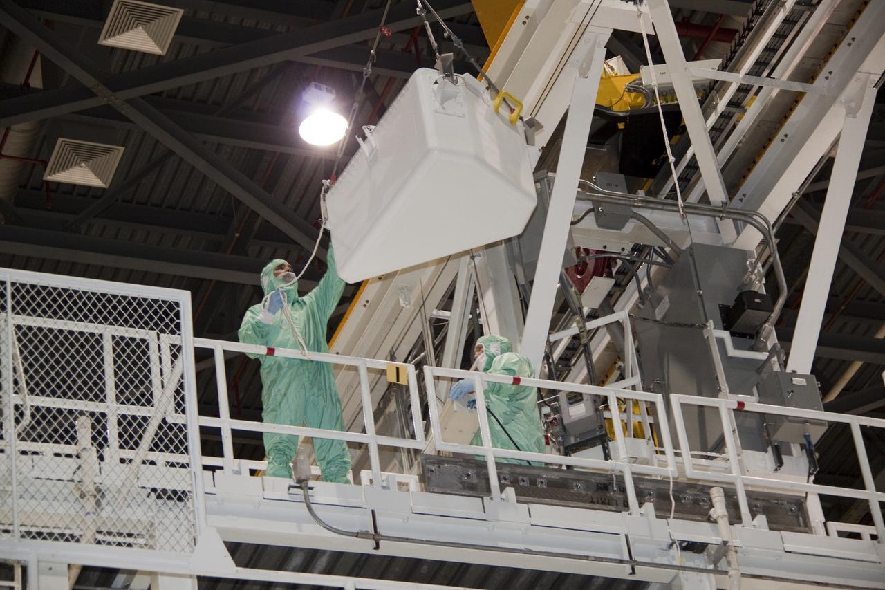 CAPE CANAVERAL, Fla. – In Orbiter Processing Facility-1 at NASA's Kennedy Space Center in Florida, workers dressed in clean room attire, known as bunny suits, guide the tool stowage assembly as it is lifted by jib crane toward the work platform on which they are standing.  The tool box is being installed into space shuttle Atlantis' payload bay.  The assembly contains tools and hardware that will be needed on the extravehicular activities, or spacewalks, conducted during the STS-132 mission. On STS-132, the six-member crew will deliver an Integrated Cargo Carrier and a Russian-built Mini-Research Module to the International Space Station.  STS-132 is the 34th mission to the station and the 132nd space shuttle mission.   Launch is targeted for May 14.  For information on the STS-132 mission, visit http:__www.nasa.gov_mission_pages_shuttle_shuttlemissions_sts132_index.html. Photo credit: NASA_Jack Pfaller