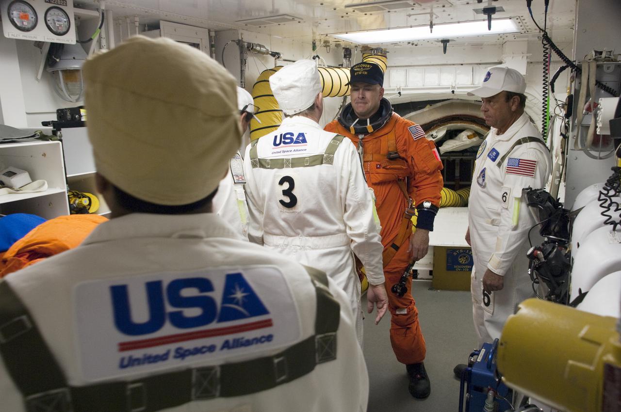 CAPE CANAVERAL, Fla. - In the White Room at Launch Pad 39A at NASA's Kennedy Space Center in Florida, United Space Alliance space suit technicians ensure that the launch-and-entry suit of STS-131 Commander Alan Poindexter fits properly before he enters space shuttle Discovery through the crew hatch in the background.  Liftoff of the STS-131 mission is set for 6:21 a.m. EDT on April 5. On STS-131, the seven-member crew will deliver the multi-purpose logistics module Leonardo, filled with supplies, a new crew sleeping quarters and science racks that will be transferred to the International Space Station's laboratories.  The crew also will switch out a gyroscope on the station’s truss, install a spare ammonia storage tank and retrieve a Japanese experiment from the station’s exterior.  STS-131 is the 33rd shuttle mission to the station and the 131st shuttle mission overall. For information on the STS-131 mission and crew, visit http:__www.nasa.gov_mission_pages_shuttle_shuttlemissions_sts131_index.html.  Photo credit: NASA_Sandra Joseph and Kevin O'Connell