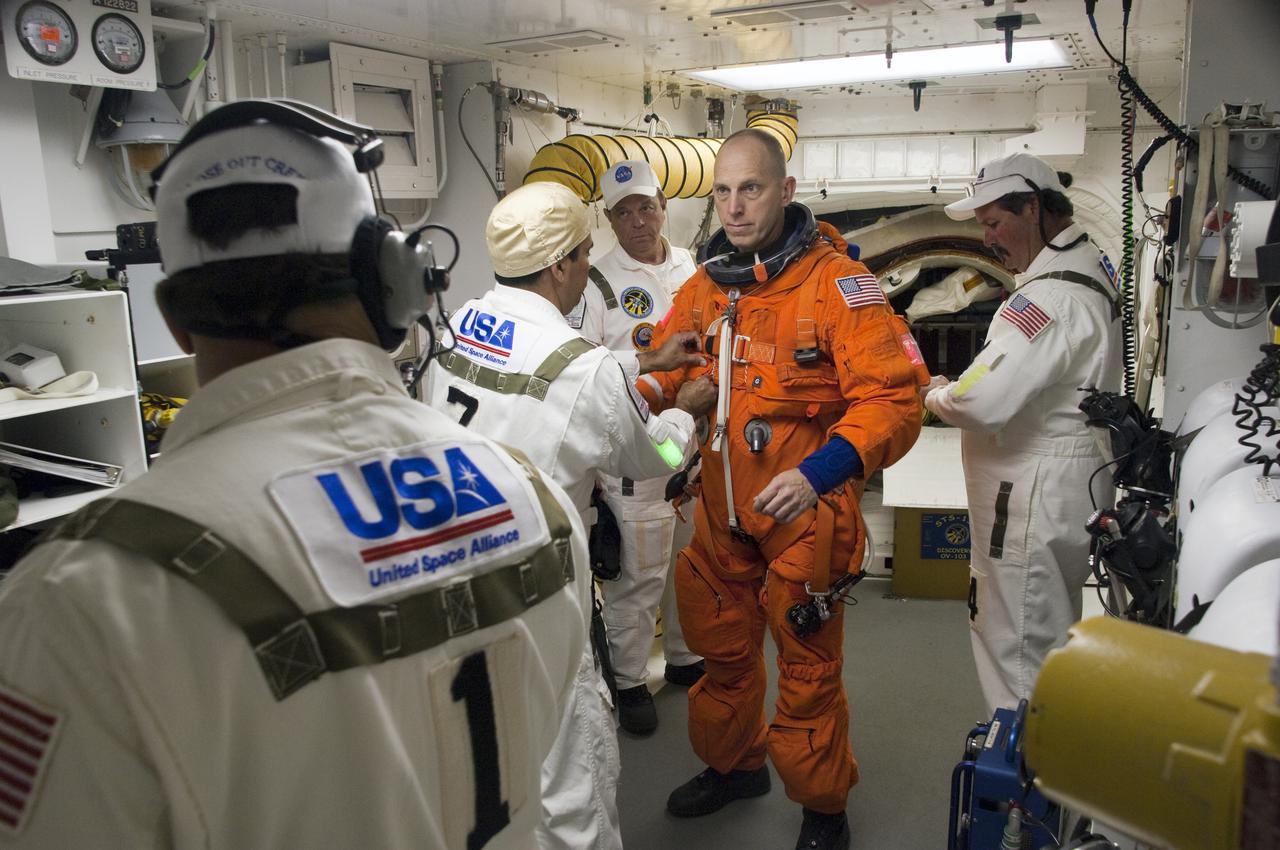 CAPE CANAVERAL, Fla. - In the White Room at Launch Pad 39A at NASA's Kennedy Space Center in Florida, United Space Alliance space suit technicians ensure that the launch-and-entry suit of STS-131 Mission Specialist Clayton Anderson fits properly before he enters space shuttle Discovery through the crew hatch in the background.  Liftoff of the STS-131 mission is set for 6:21 a.m. EDT on April 5. On STS-131, the seven-member crew will deliver the multi-purpose logistics module Leonardo, filled with supplies, a new crew sleeping quarters and science racks that will be transferred to the International Space Station's laboratories.  The crew also will switch out a gyroscope on the station’s truss, install a spare ammonia storage tank and retrieve a Japanese experiment from the station’s exterior.  STS-131 is the 33rd shuttle mission to the station and the 131st shuttle mission overall. For information on the STS-131 mission and crew, visit http:__www.nasa.gov_mission_pages_shuttle_shuttlemissions_sts131_index.html.  Photo credit: NASA_Sandra Joseph and Kevin O'Connell