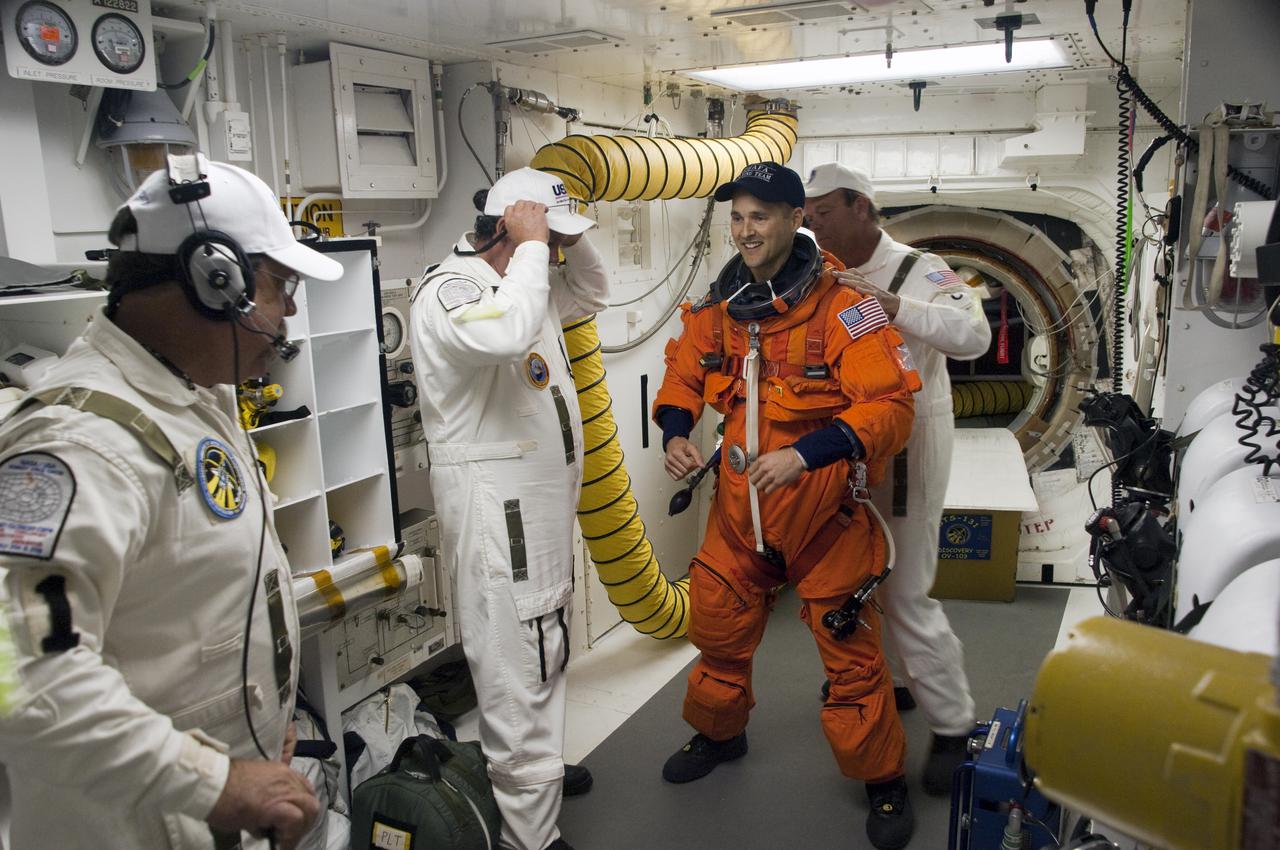 CAPE CANAVERAL, Fla. - In the White Room at Launch Pad 39A at NASA's Kennedy Space Center in Florida, United Space Alliance space suit technicians ensure that the launch-and-entry suit of STS-131 Pilot James P. Dutton Jr. fits properly before he enters space shuttle Discovery through the crew hatch in the background.  Liftoff of the STS-131 mission is set for 6:21 a.m. EDT on April 5. On STS-131, the seven-member crew will deliver the multi-purpose logistics module Leonardo, filled with supplies, a new crew sleeping quarters and science racks that will be transferred to the International Space Station's laboratories.  The crew also will switch out a gyroscope on the station’s truss, install a spare ammonia storage tank and retrieve a Japanese experiment from the station’s exterior.  STS-131 is the 33rd shuttle mission to the station and the 131st shuttle mission overall. For information on the STS-131 mission and crew, visit http:__www.nasa.gov_mission_pages_shuttle_shuttlemissions_sts131_index.html.  Photo credit: NASA_Sandra Joseph and Kevin O'Connell