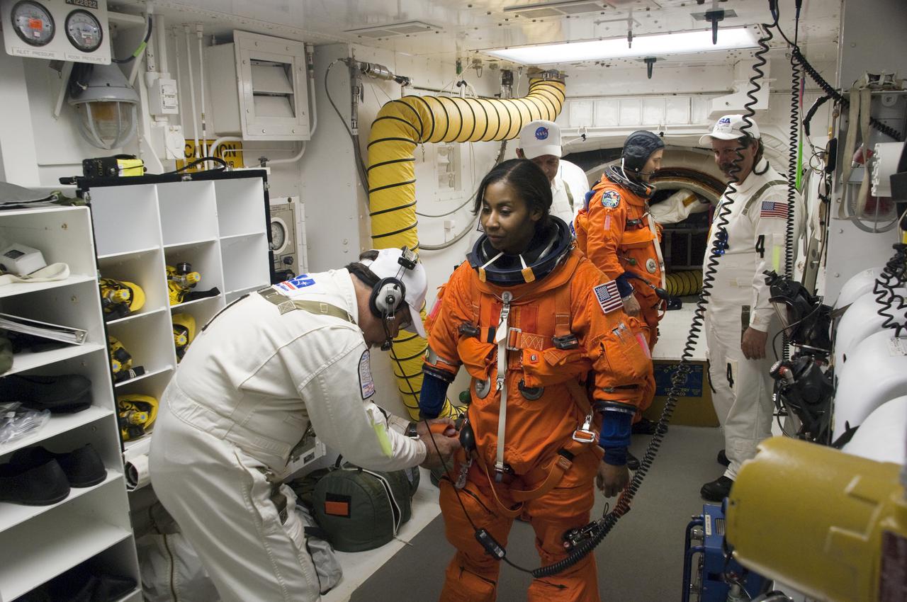 CAPE CANAVERAL, Fla. - In the White Room at Launch Pad 39A at NASA's Kennedy Space Center in Florida, United Space Alliance space suit technicians ensure that the launch-and-entry suit of STS-131 Mission Specialist Stephanie Wilson fits properly before she enters space shuttle Discovery through the crew hatch in the background.  Liftoff of the STS-131 mission is set for 6:21 a.m. EDT on April 5. On STS-131, the seven-member crew will deliver the multi-purpose logistics module Leonardo, filled with supplies, a new crew sleeping quarters and science racks that will be transferred to the International Space Station's laboratories.  The crew also will switch out a gyroscope on the station’s truss, install a spare ammonia storage tank and retrieve a Japanese experiment from the station’s exterior.  STS-131 is the 33rd shuttle mission to the station and the 131st shuttle mission overall. For information on the STS-131 mission and crew, visit http:__www.nasa.gov_mission_pages_shuttle_shuttlemissions_sts131_index.html.  Photo credit: NASA_Sandra Joseph and Kevin O'Connell