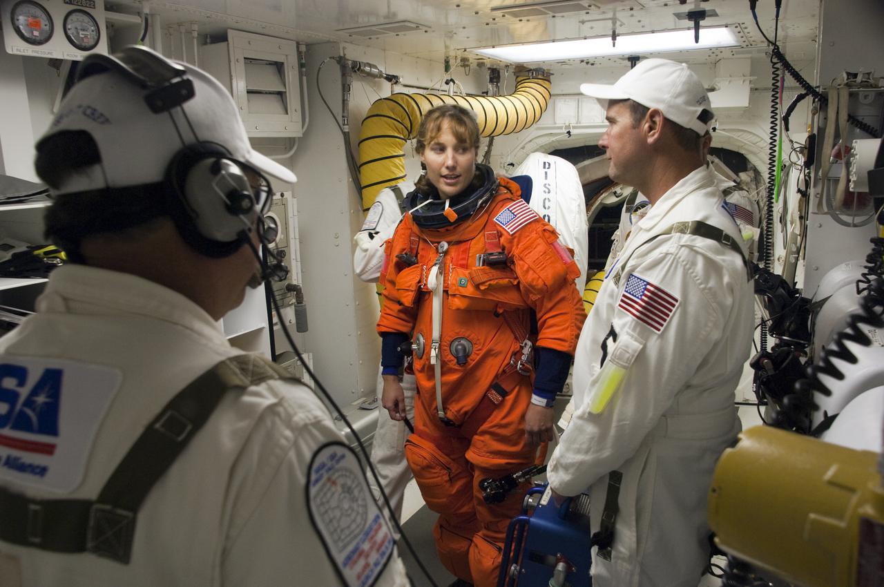CAPE CANAVERAL, Fla. - In the White Room at Launch Pad 39A at NASA's Kennedy Space Center in Florida, United Space Alliance space suit technicians ensure that the launch-and-entry suit of STS-131 Mission Specialist Dorothy Metcalf-Lindenburger fits properly before she enters space shuttle Discovery through the crew hatch in the background.  Liftoff of the STS-131 mission is set for 6:21 a.m. EDT on April 5. On STS-131, the seven-member crew will deliver the multi-purpose logistics module Leonardo, filled with supplies, a new crew sleeping quarters and science racks that will be transferred to the International Space Station's laboratories.  The crew also will switch out a gyroscope on the station’s truss, install a spare ammonia storage tank and retrieve a Japanese experiment from the station’s exterior.  STS-131 is the 33rd shuttle mission to the station and the 131st shuttle mission overall. For information on the STS-131 mission and crew, visit http:__www.nasa.gov_mission_pages_shuttle_shuttlemissions_sts131_index.html.  Photo credit: NASA_Sandra Joseph and Kevin O'Connell