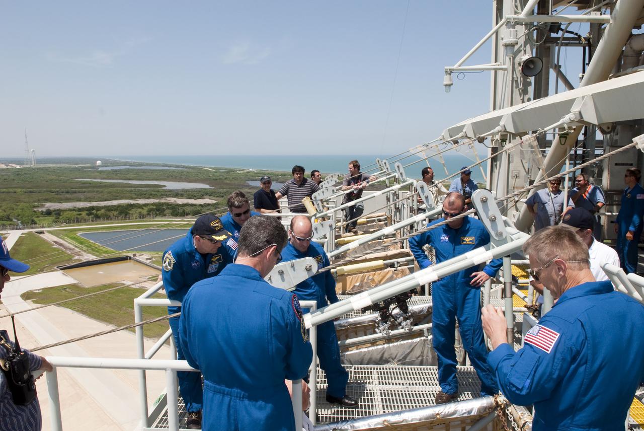 CAPE CANAVERAL, Fla. - On Launch Pad 39A at NASA's Kennedy Space Center, the members of space shuttle Atlantis' STS-132 crew receive instruction on the operation of the pad's slidewire basket system during emergency exit training.  The pad's escape system includes seven baskets suspended from seven slidewires that extend from the fixed service structure to a landing zone 1,200 feet west of the pad.  In the blue flight suits, from left, facing the camera, are Commander Ken Ham; Mission Specialists Steve Bowen and Garrett Reisman; and Pilot Tony Antonelli.  Facing away from the camera are Mission Specialists Michael Good, left, and Piers Sellers.  The crew is participating in training in preparation for their Terminal Countdown Demonstration Test, or TCDT, a dress rehearsal for launch.  TCDT provides each shuttle crew and launch team the opportunity to participate in various simulated countdown activities, including equipment familiarization and emergency procedures.  On the STS-132 mission, the six-member crew will deliver an Integrated Cargo Carrier, or ICC, and the Russian-built Mini-Research Module-1, or MRM-1, to the International Space Station aboard space shuttle Atlantis.  The ICC is an unpressurized flat bed pallet and keel yoke assembly used to support the transfer of exterior cargo from the shuttle to the space station.  The MRM-1, known as Rassvet, is the second in a series of new pressurized components for Russia and will be permanently attached to the Earth-facing port of the Zarya control module. Rassvet, which translates to 'dawn,' will be used for cargo storage and will provide an additional docking port to the station.  STS-132 is the 34th mission to the station and the 132nd shuttle mission overall.   Atlantis is targeted to launch on May 14 at 2:19 p.m.  For information on the STS-132 mission, visit http:__www.nasa.gov_mission_pages_shuttle_shuttlemissions_sts132_index.html. Photo credit: NASA_Jim Grossmann